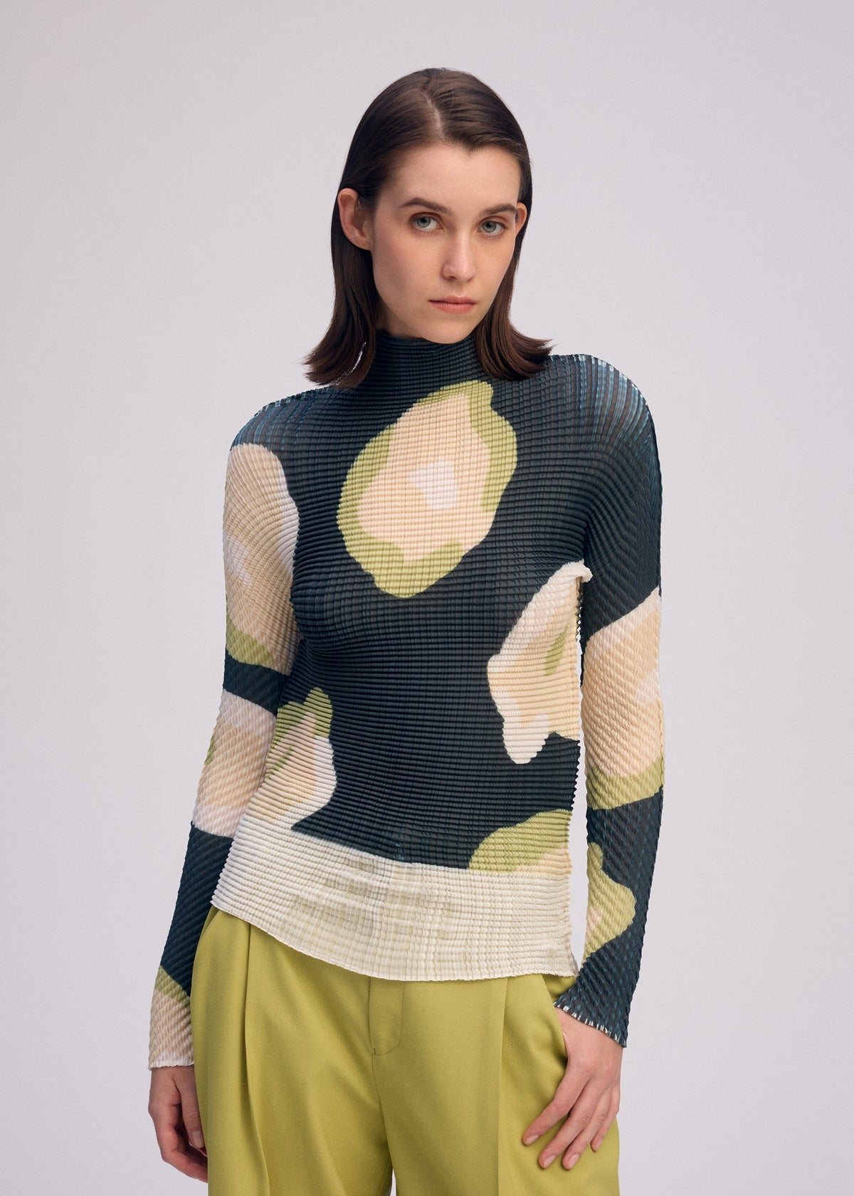 A model wears the ISSEY MIYAKE VERVE PLEATS TOP shirt.
