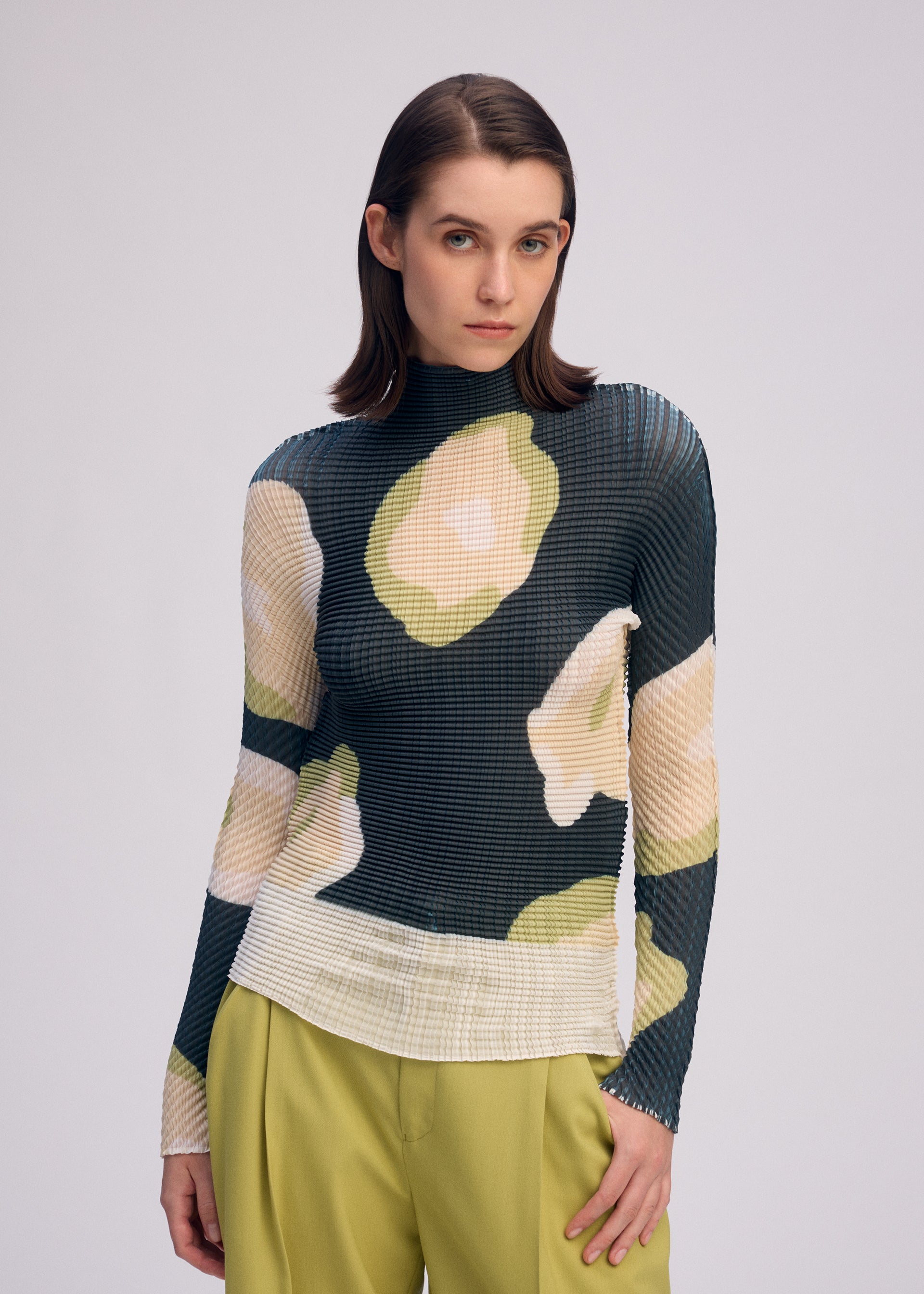 A model wears the ISSEY MIYAKE VERVE PLEATS TOP shirt.
