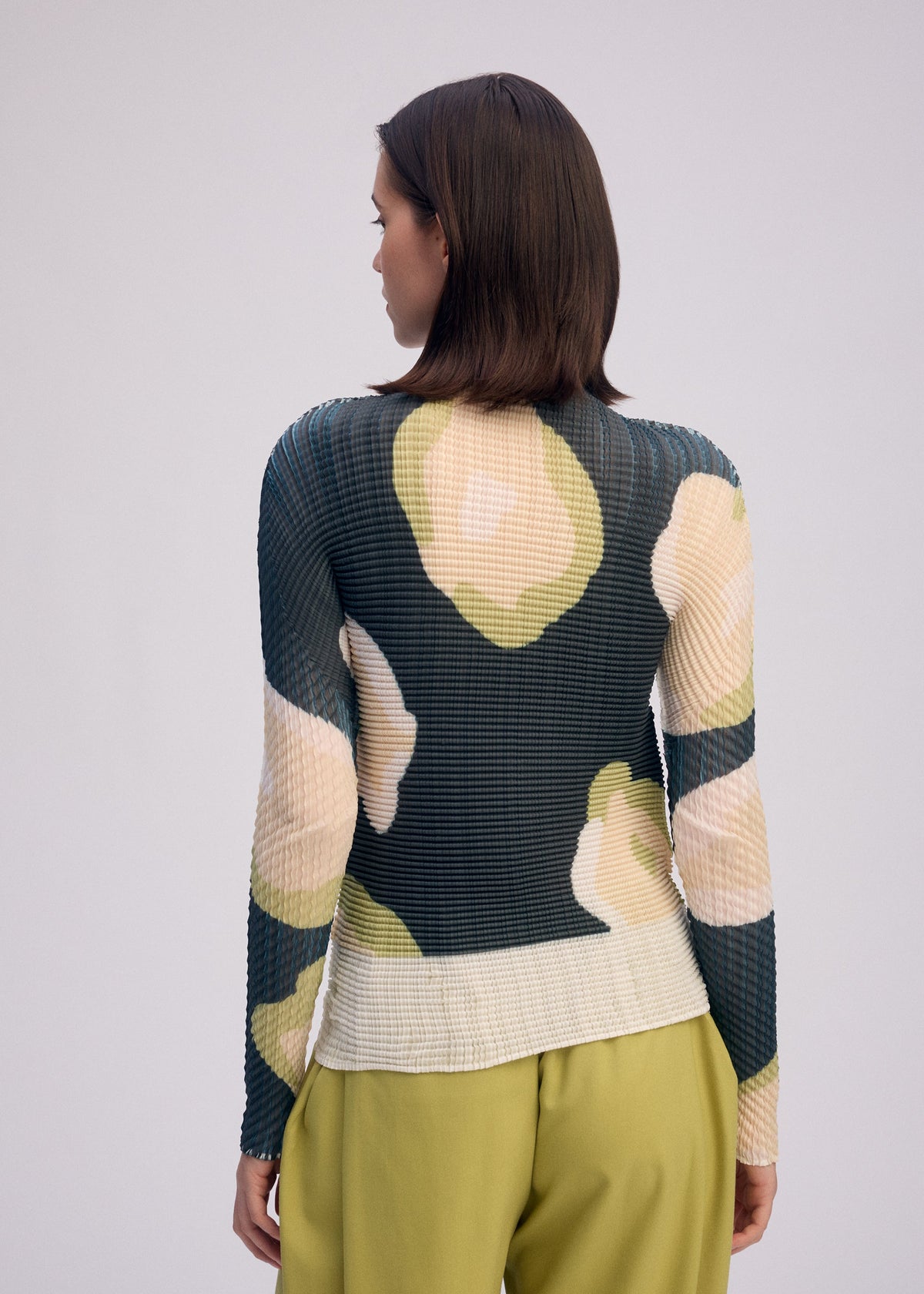 A model wears the ISSEY MIYAKE VERVE PLEATS TOP shirt.