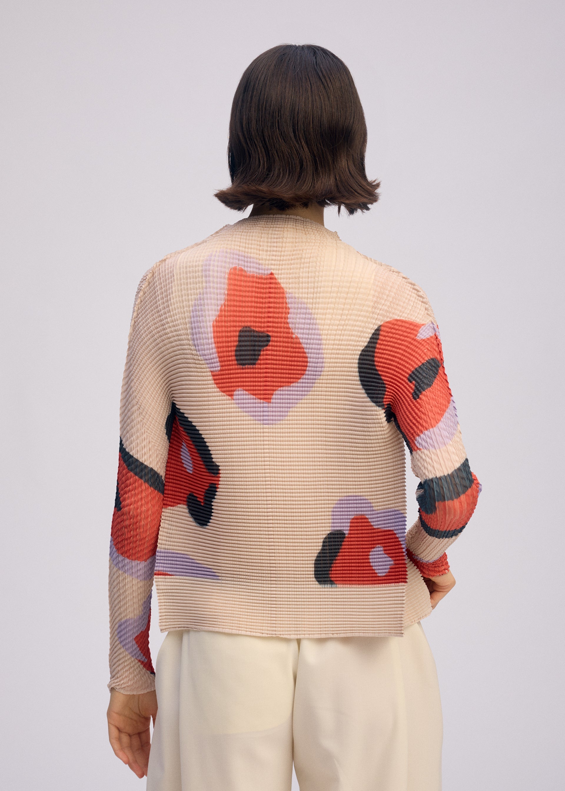 A model wears the ISSEY MIYAKE VERVE PLEATS TOP shirt.
