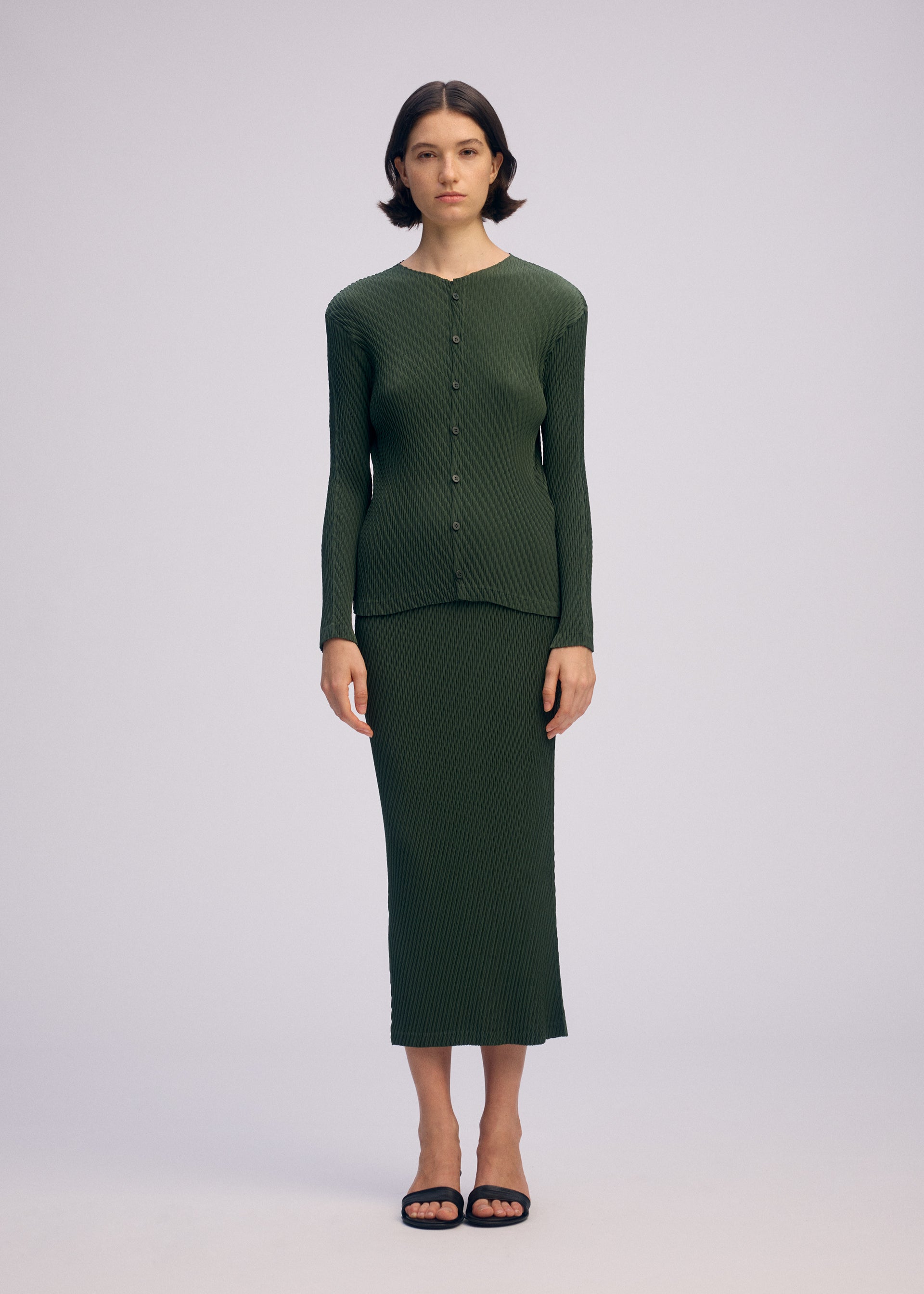 A model wears the ISSEY MIYAKE RHOMBUS PLEATS cardigan.