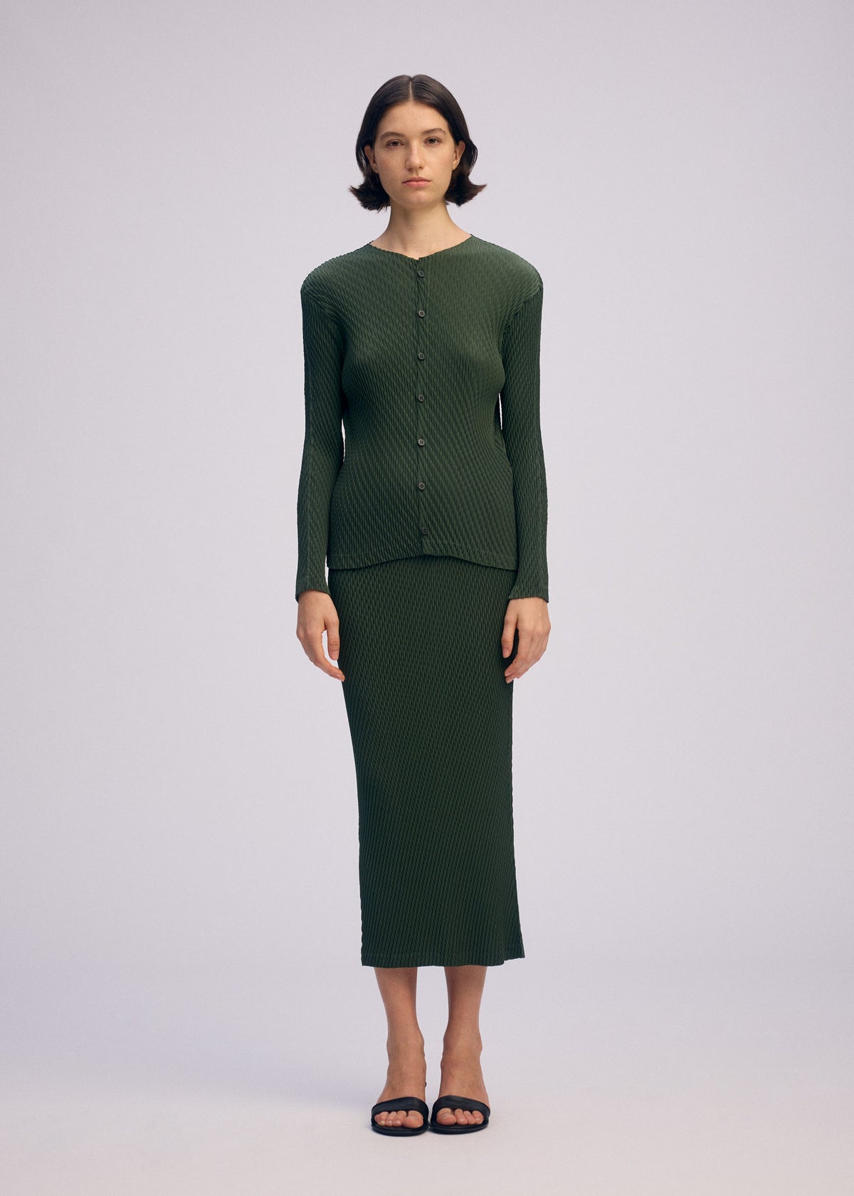 A model wears the ISSEY MIYAKE RHOMBUS PLEATS cardigan.