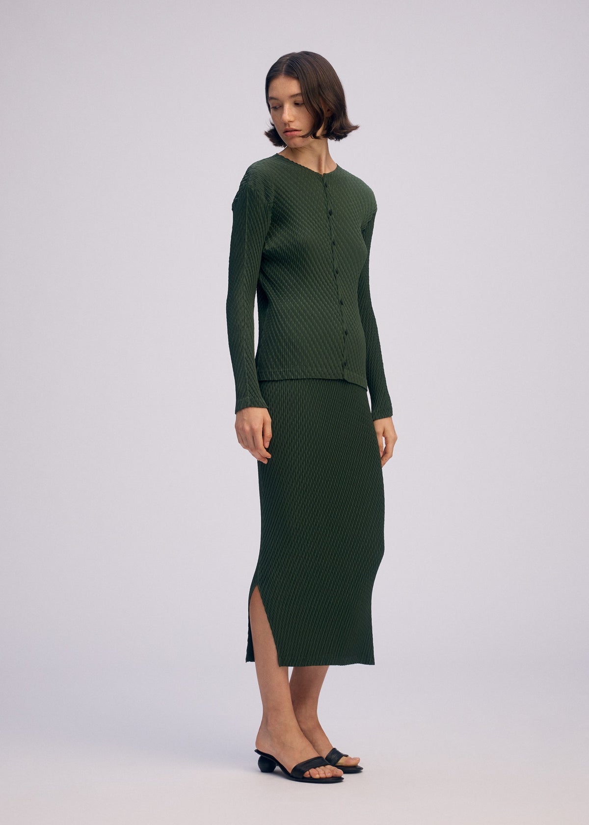 A model wears the ISSEY MIYAKE RHOMBUS PLEATS cardigan.