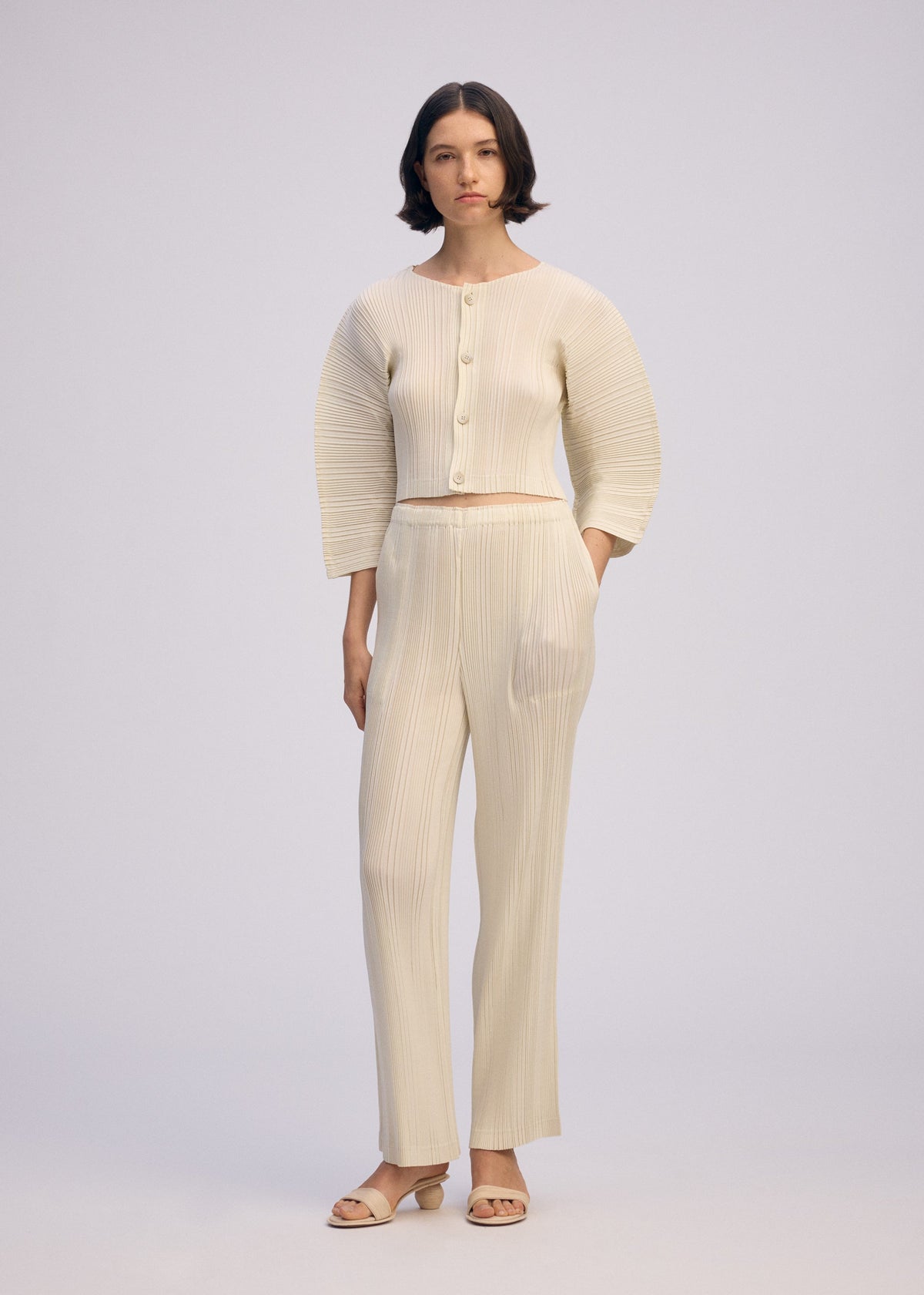 A model wears the ISSEY MIYAKE LINEN LIKE RIB PLEATS cardigan.