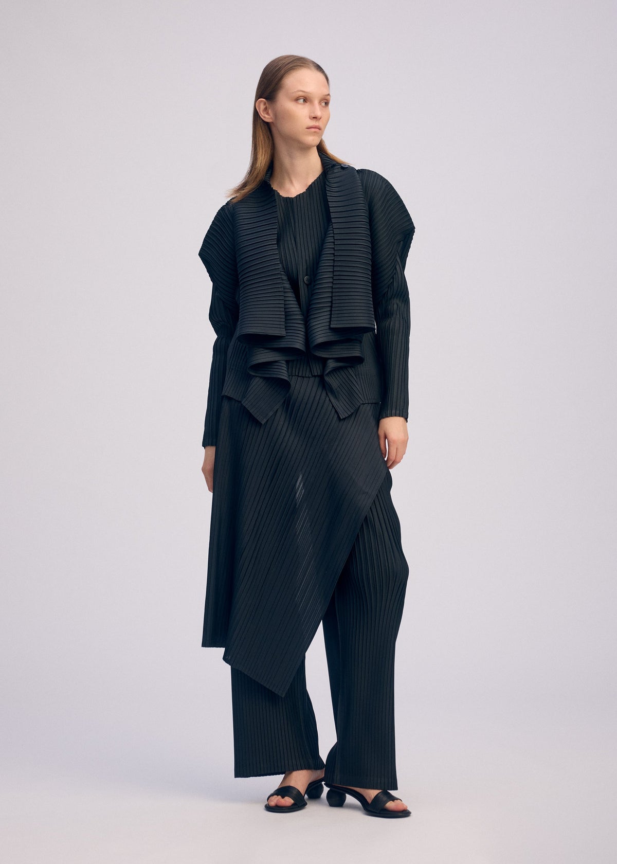 A model wears the ISSEY MIYAKE PLEATED ON PLEATS cardigan.