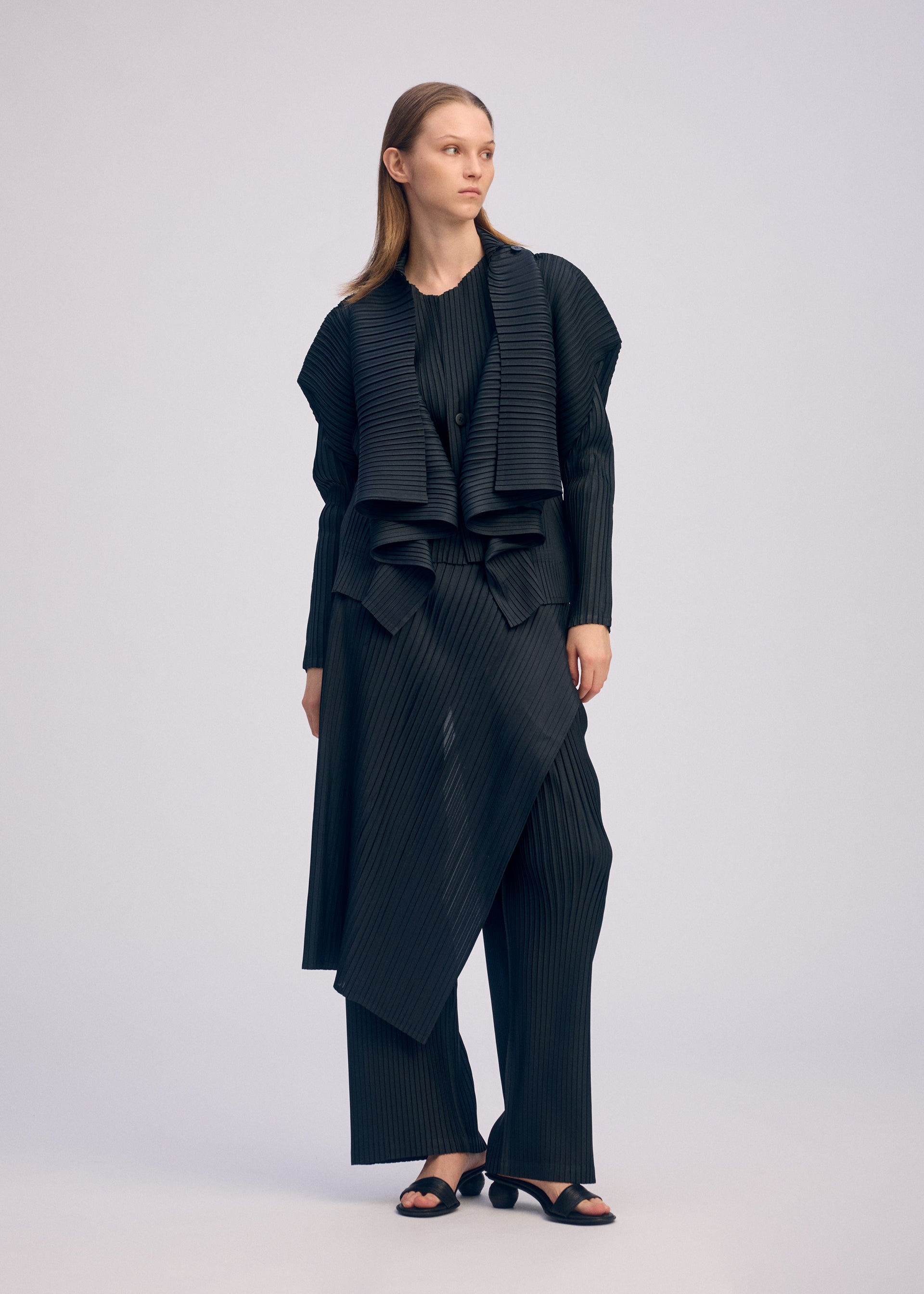 A model wears the ISSEY MIYAKE PLEATED ON PLEATS cardigan.