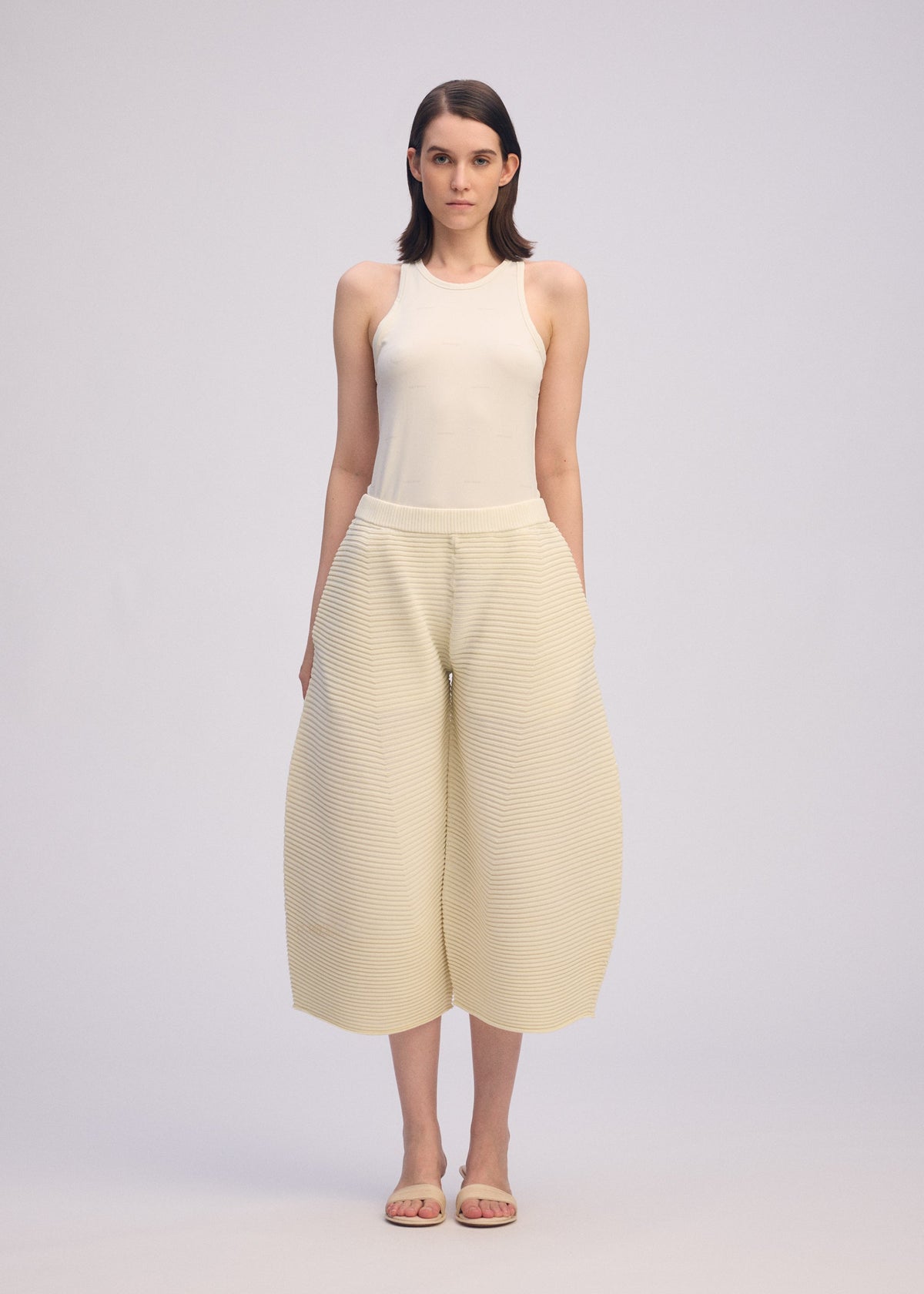 A model wears the ISSEY MIYAKE CORRUGATED KNIT trousers.