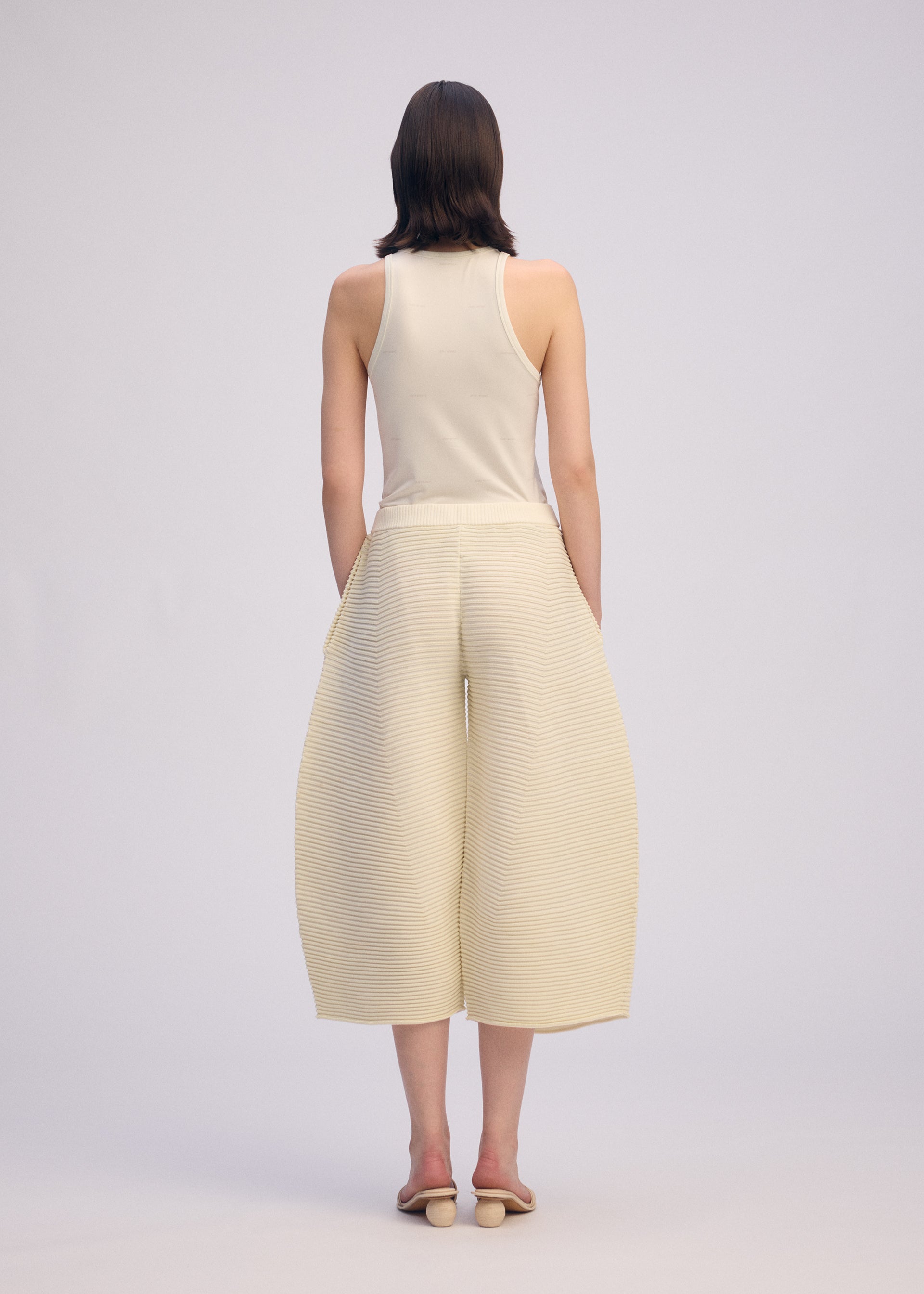 A model wears the ISSEY MIYAKE CORRUGATED KNIT trousers.