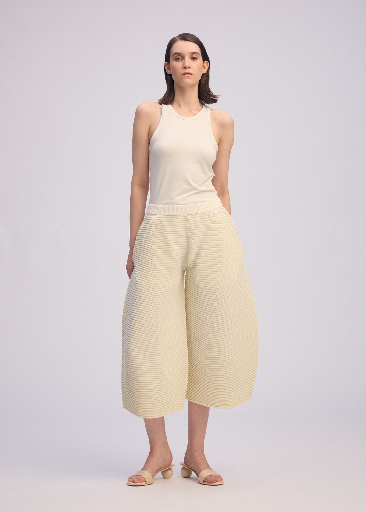 A model wears the ISSEY MIYAKE CORRUGATED KNIT trousers.
