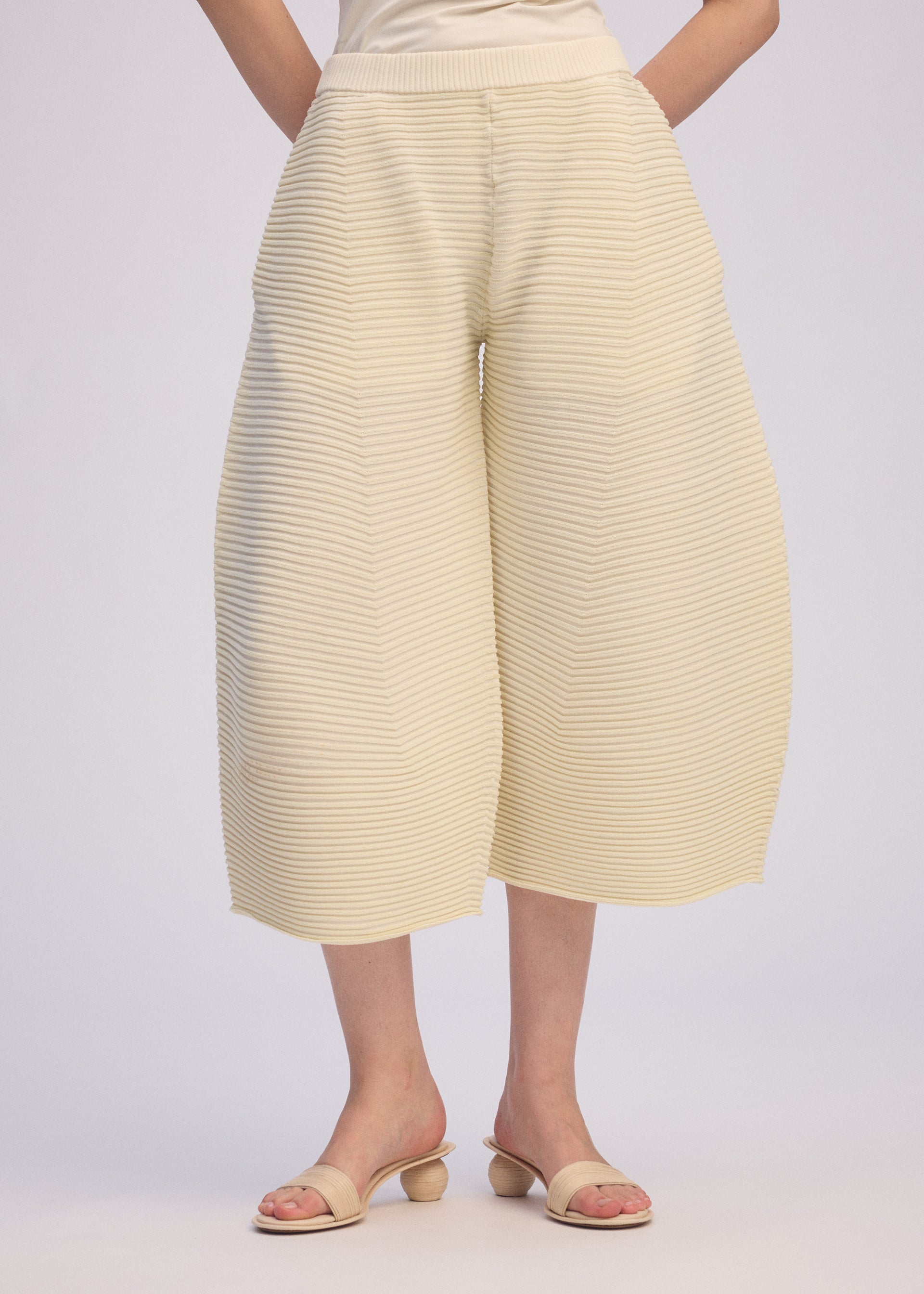 A model wears the ISSEY MIYAKE CORRUGATED KNIT trousers.
