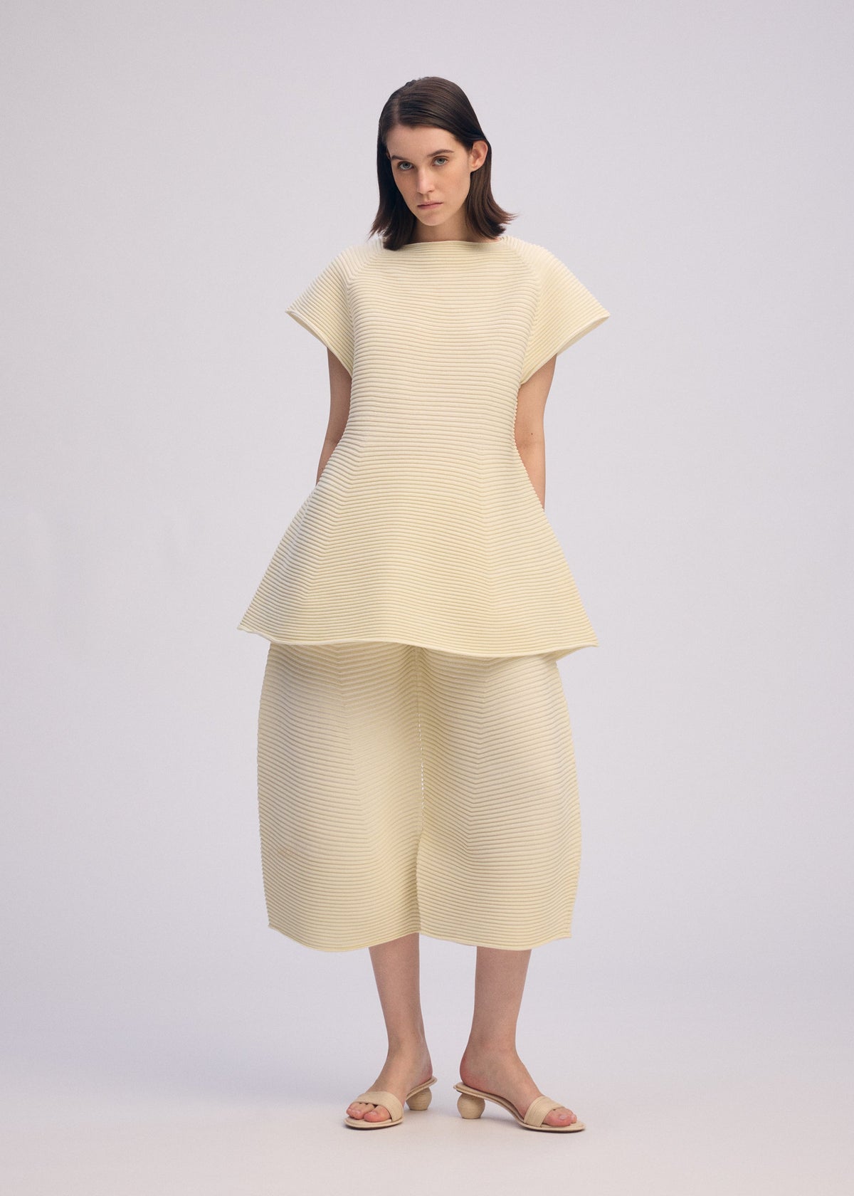 A model wears the ISSEY MIYAKE CORRUGATED KNIT trousers.