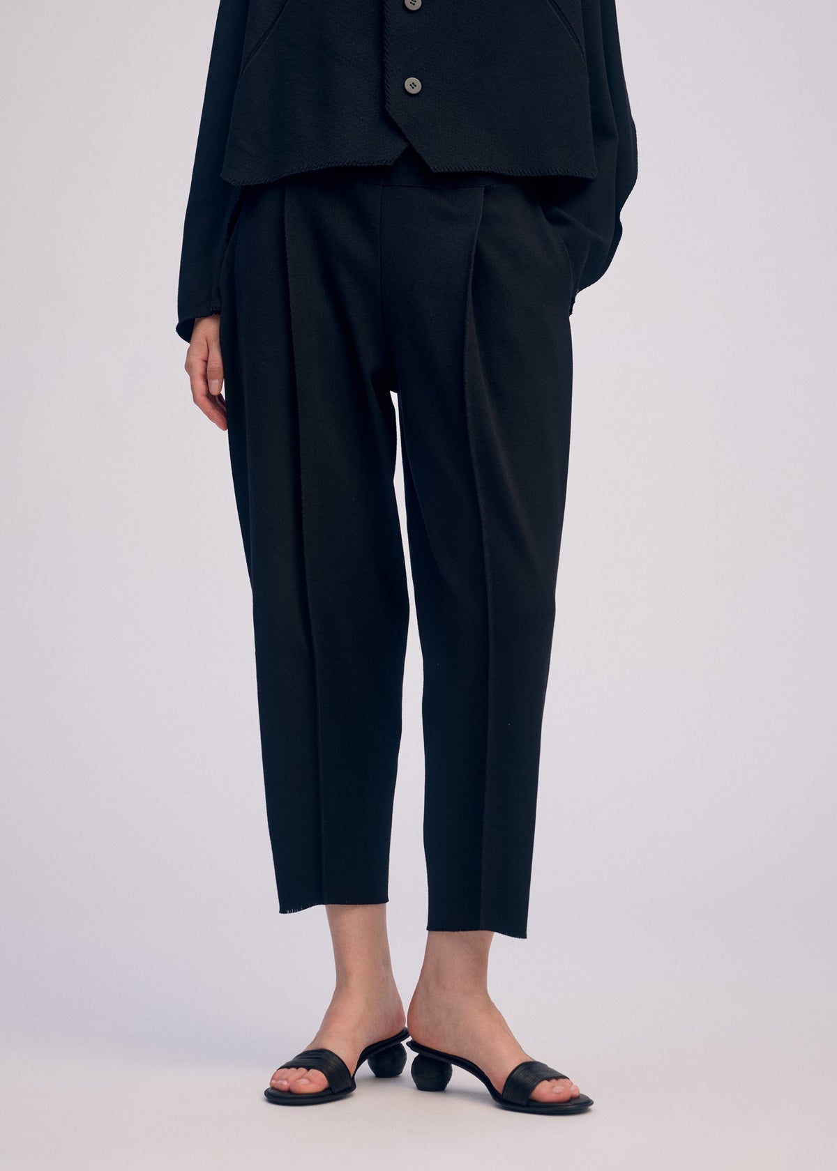 A model wears the ISSEY MIYAKE CAMPAGNE trousers.