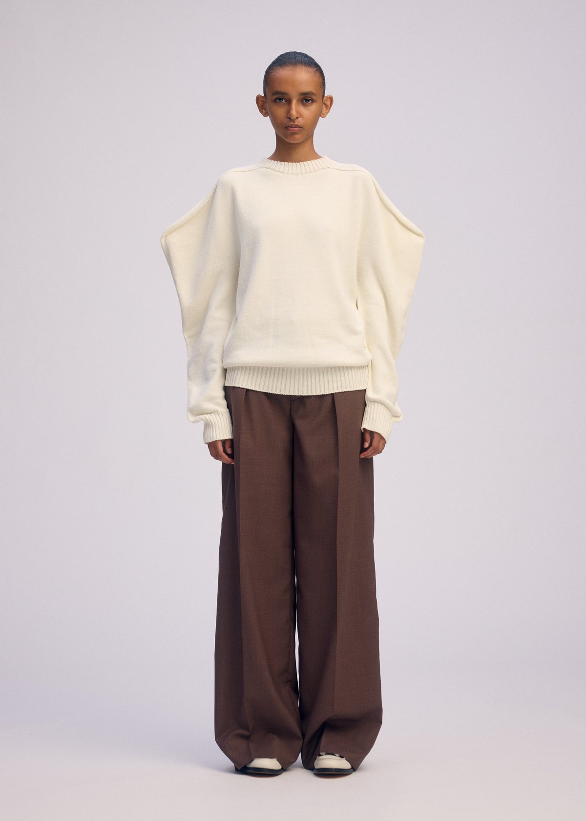 A model wears the ISSEY MIYAKE AKIMBO KNIT clothing.