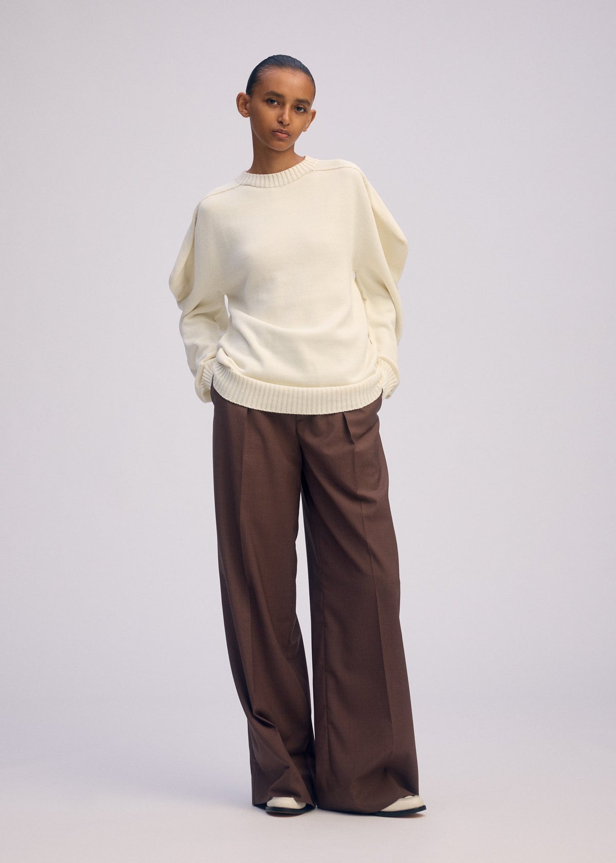 A model wears the ISSEY MIYAKE AKIMBO KNIT clothing.