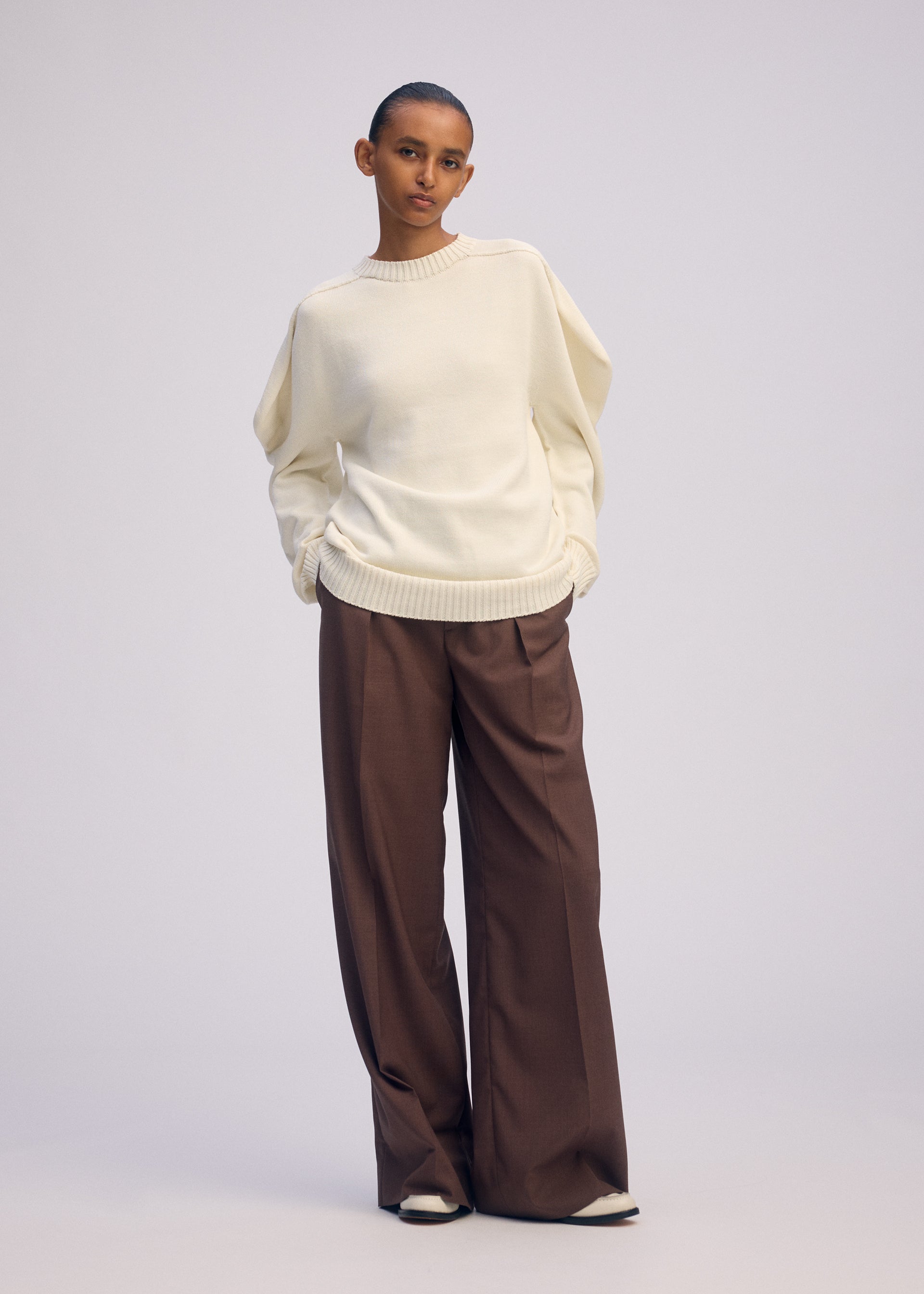 A model wears the ISSEY MIYAKE AKIMBO KNIT clothing.