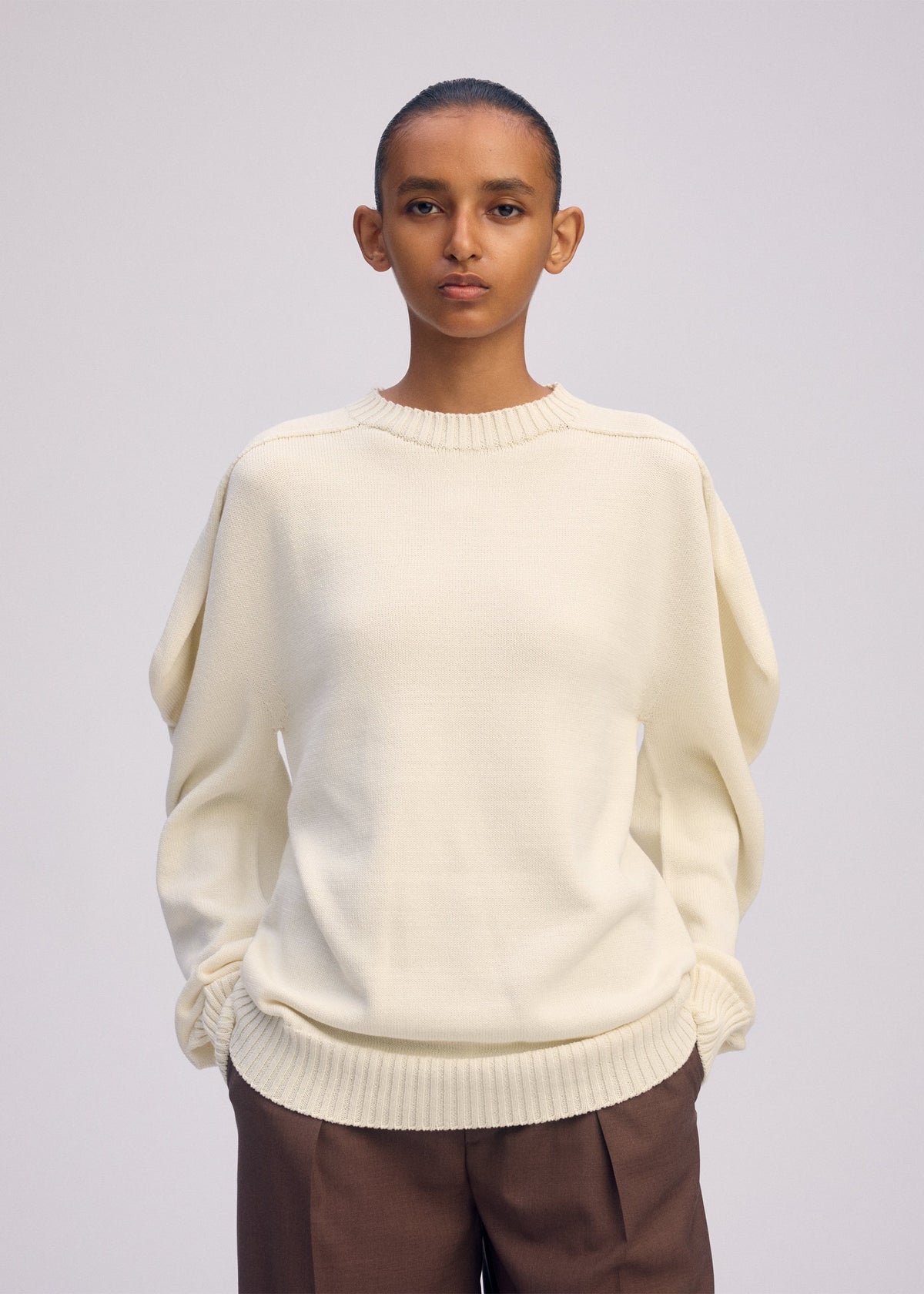 A model wears the ISSEY MIYAKE AKIMBO KNIT clothing.