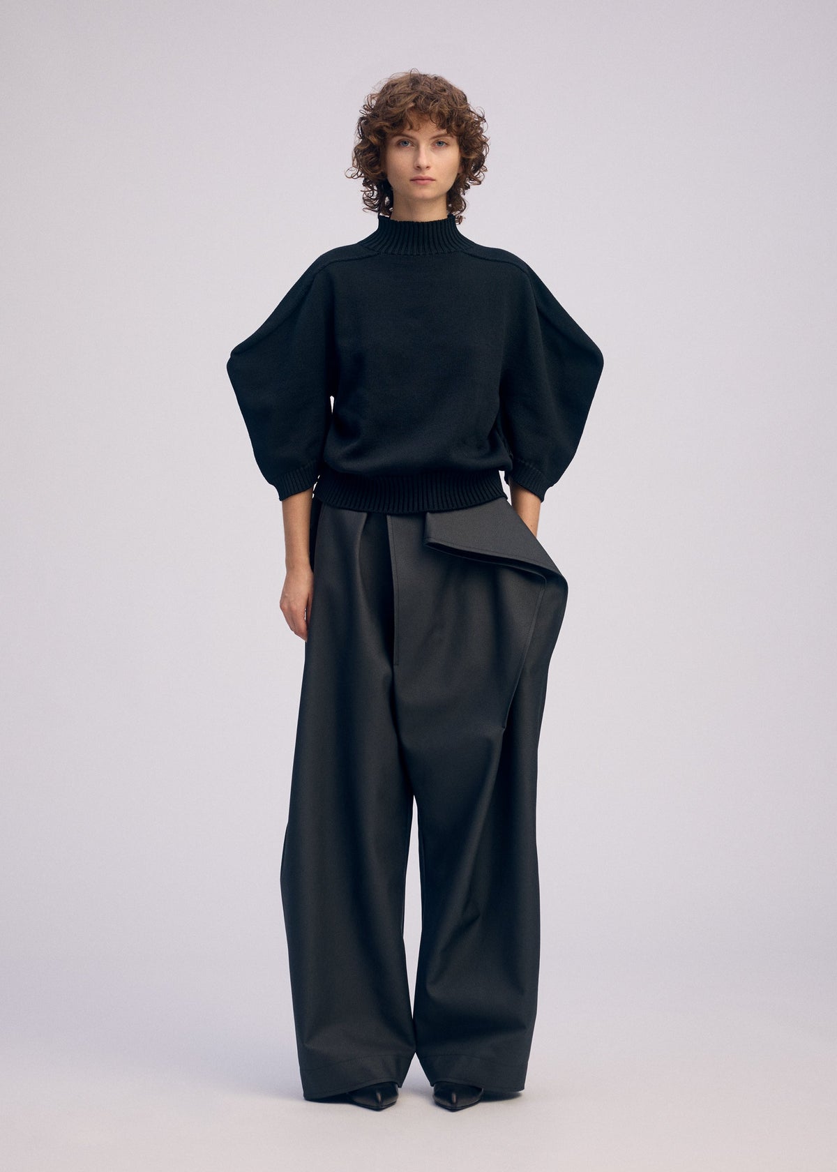 A model wears the ISSEY MIYAKE AKIMBO KNIT clothing.