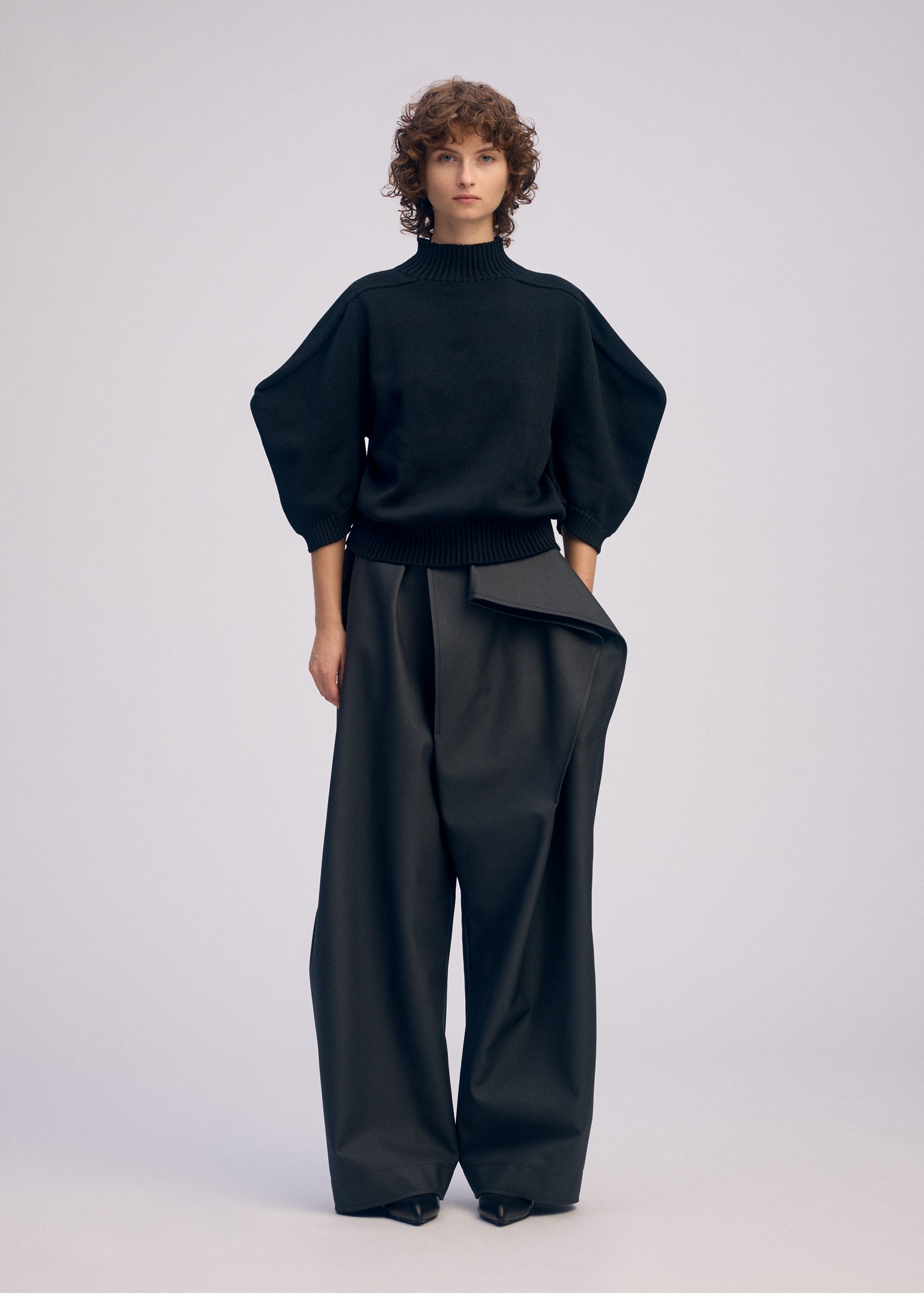 A model wears the ISSEY MIYAKE AKIMBO KNIT clothing.