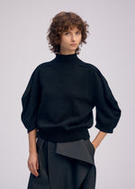 A model wears the ISSEY MIYAKE AKIMBO KNIT clothing.