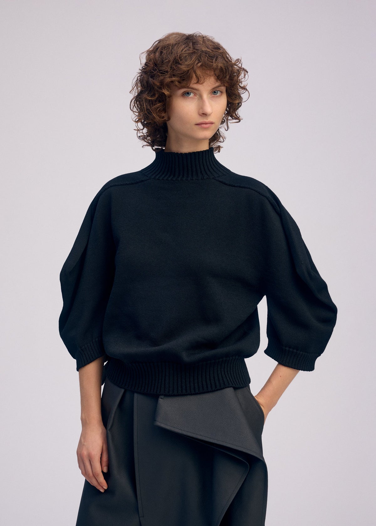 A model wears the ISSEY MIYAKE AKIMBO KNIT clothing.