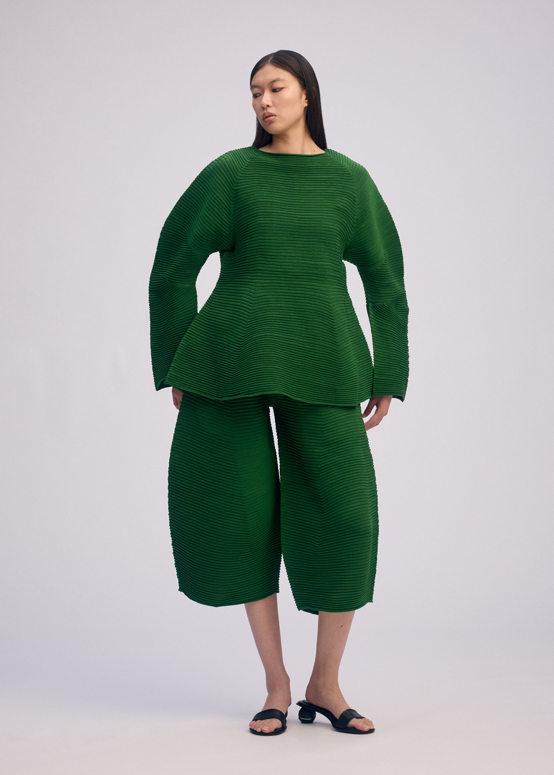 A model wears the ISSEY MIYAKE CORRUGATED KNIT top.
