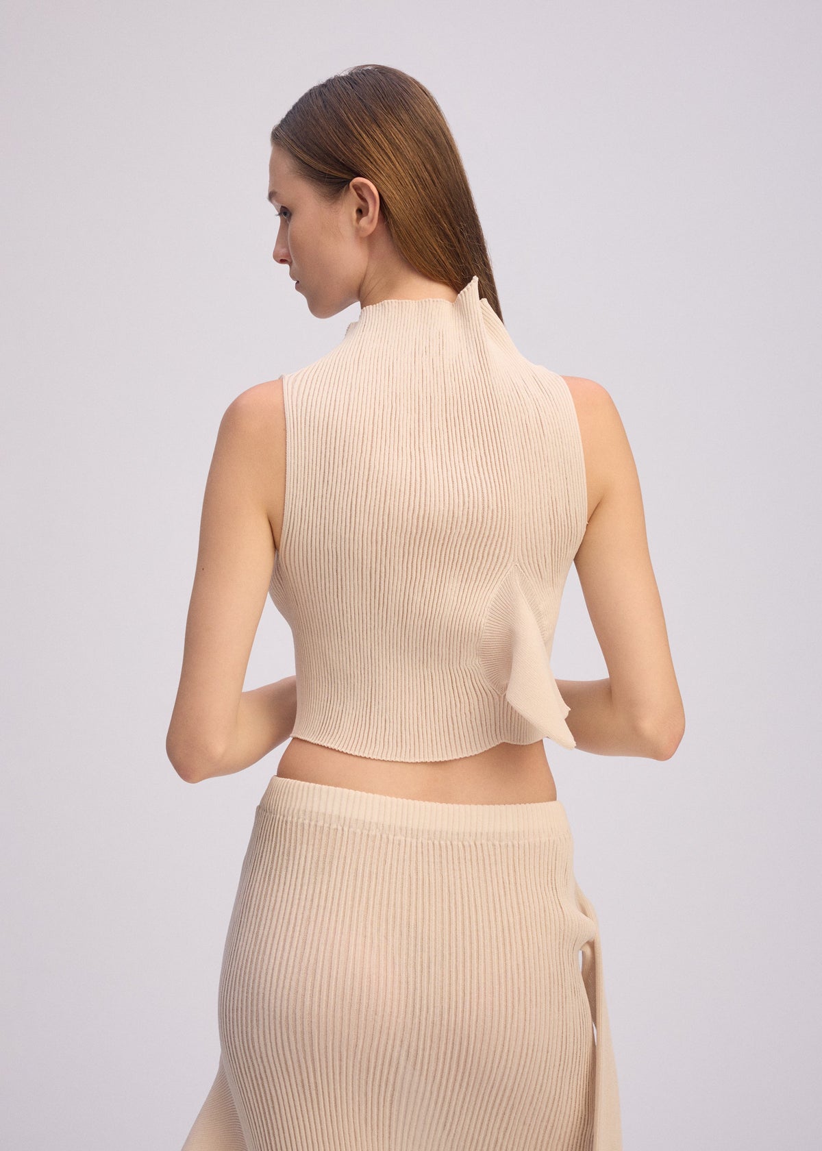 A model wears the ISSEY MIYAKE ADVENTITIOUS HIGH NECKS top.