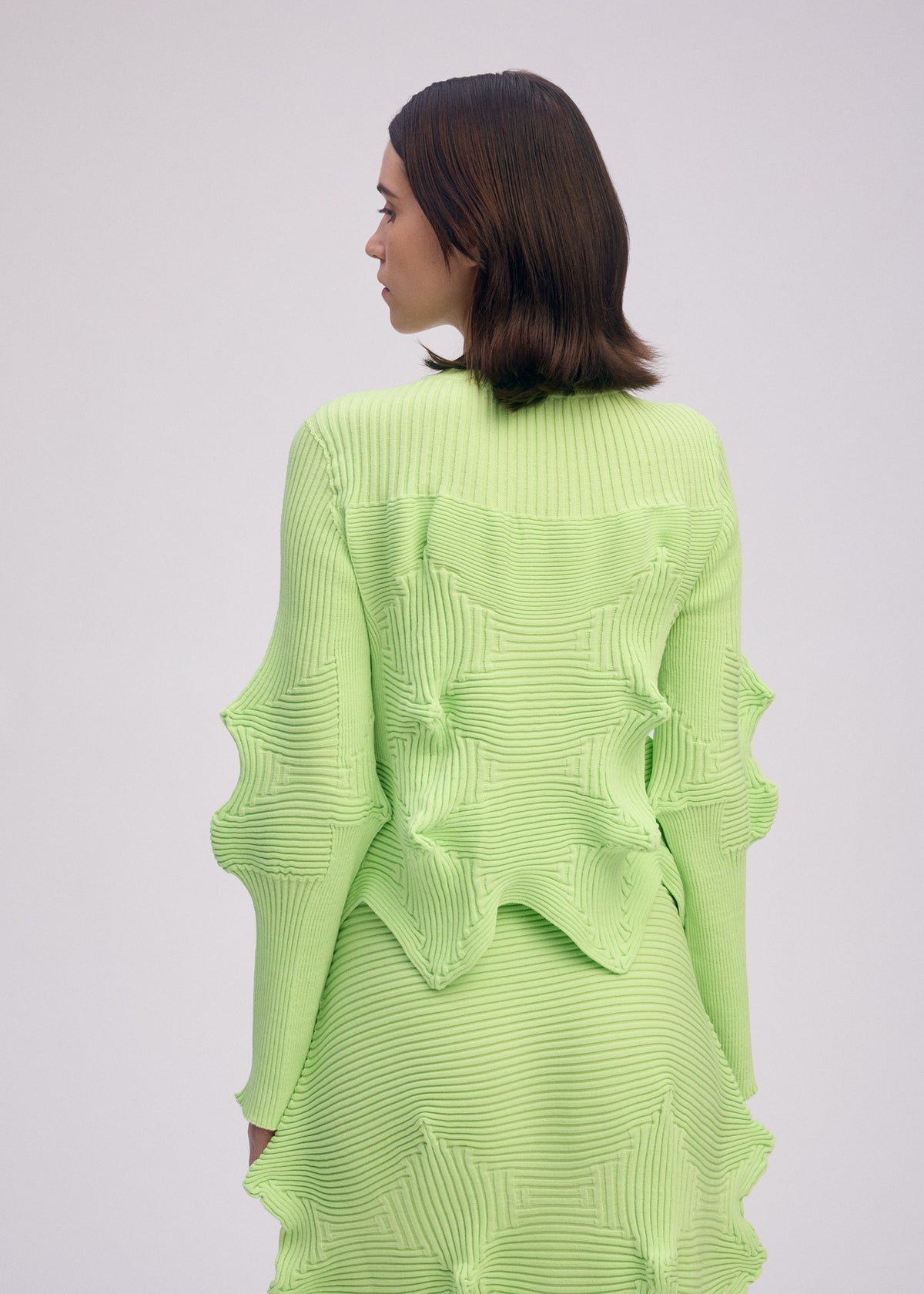 A model wears the ISSEY MIYAKE LINKAGE cardigan.