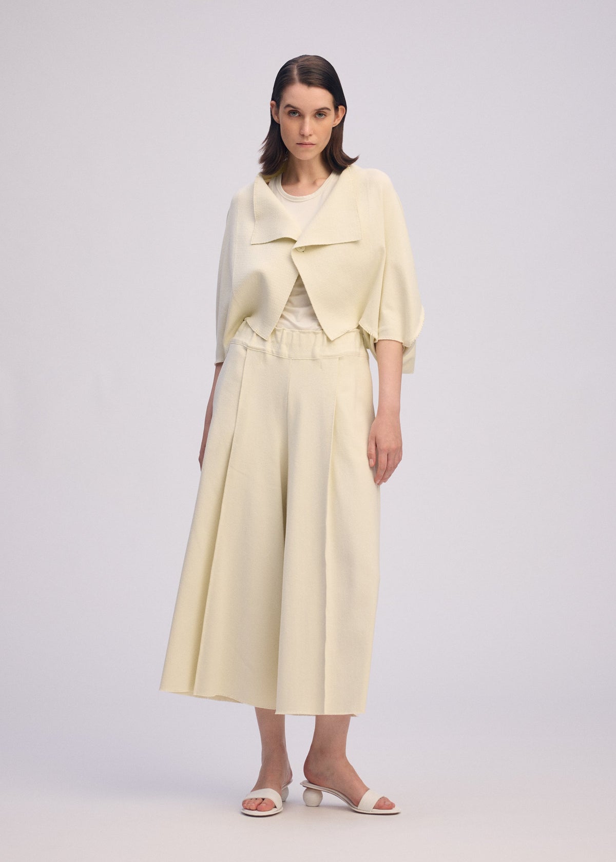 A model wears the ISSEY MIYAKE CAMPAGNE cardigan.