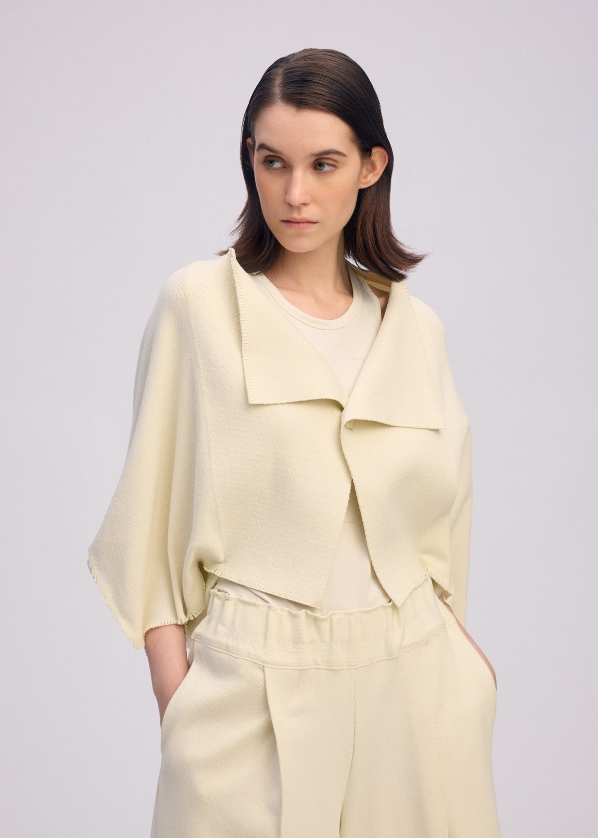 A model wears the ISSEY MIYAKE CAMPAGNE cardigan.