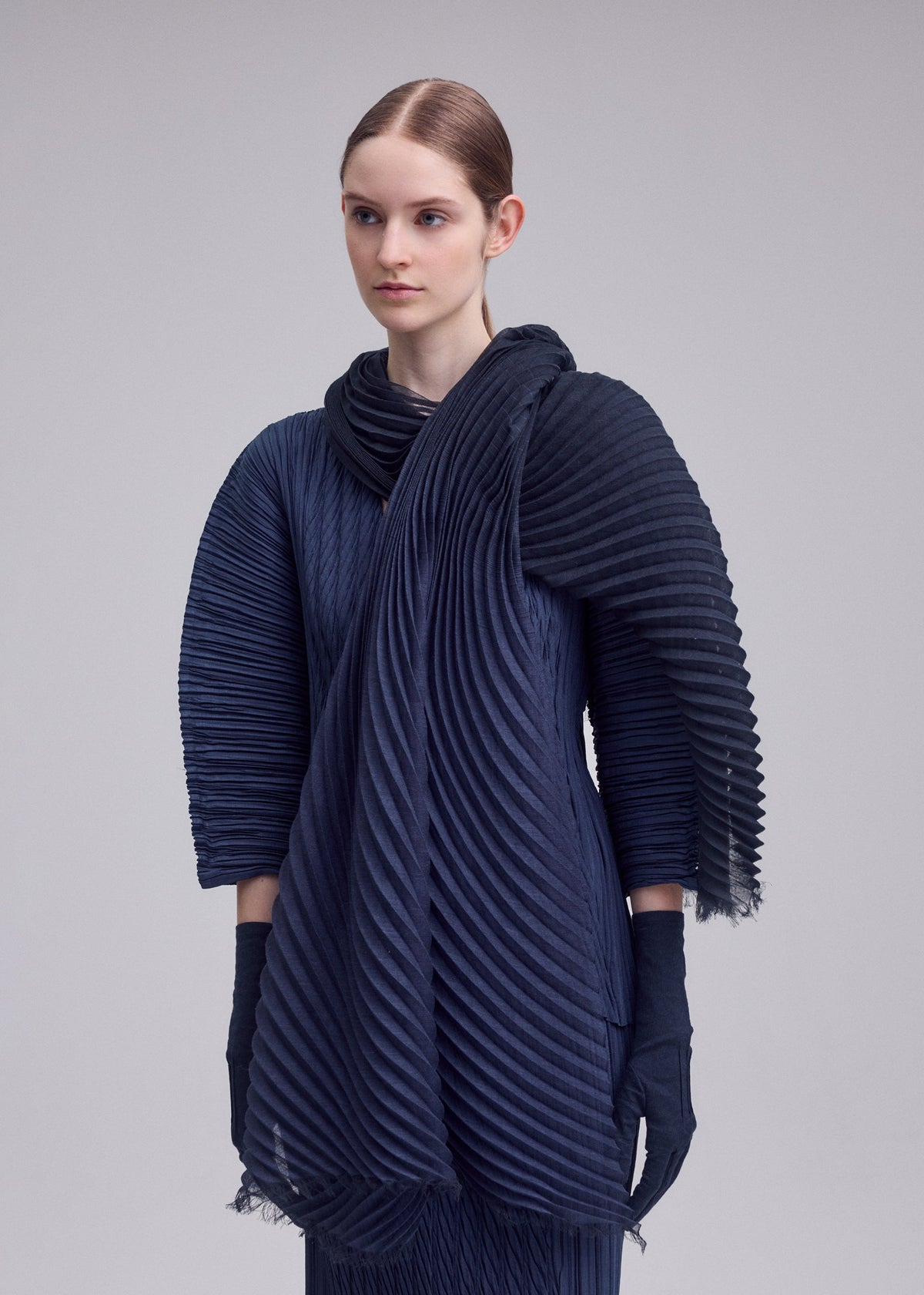 A model wears the ISSEY MIYAKE GRADATION RAMIE PLEATS STOLE gradation-ramie-pleats-stole-stole-black-hued.