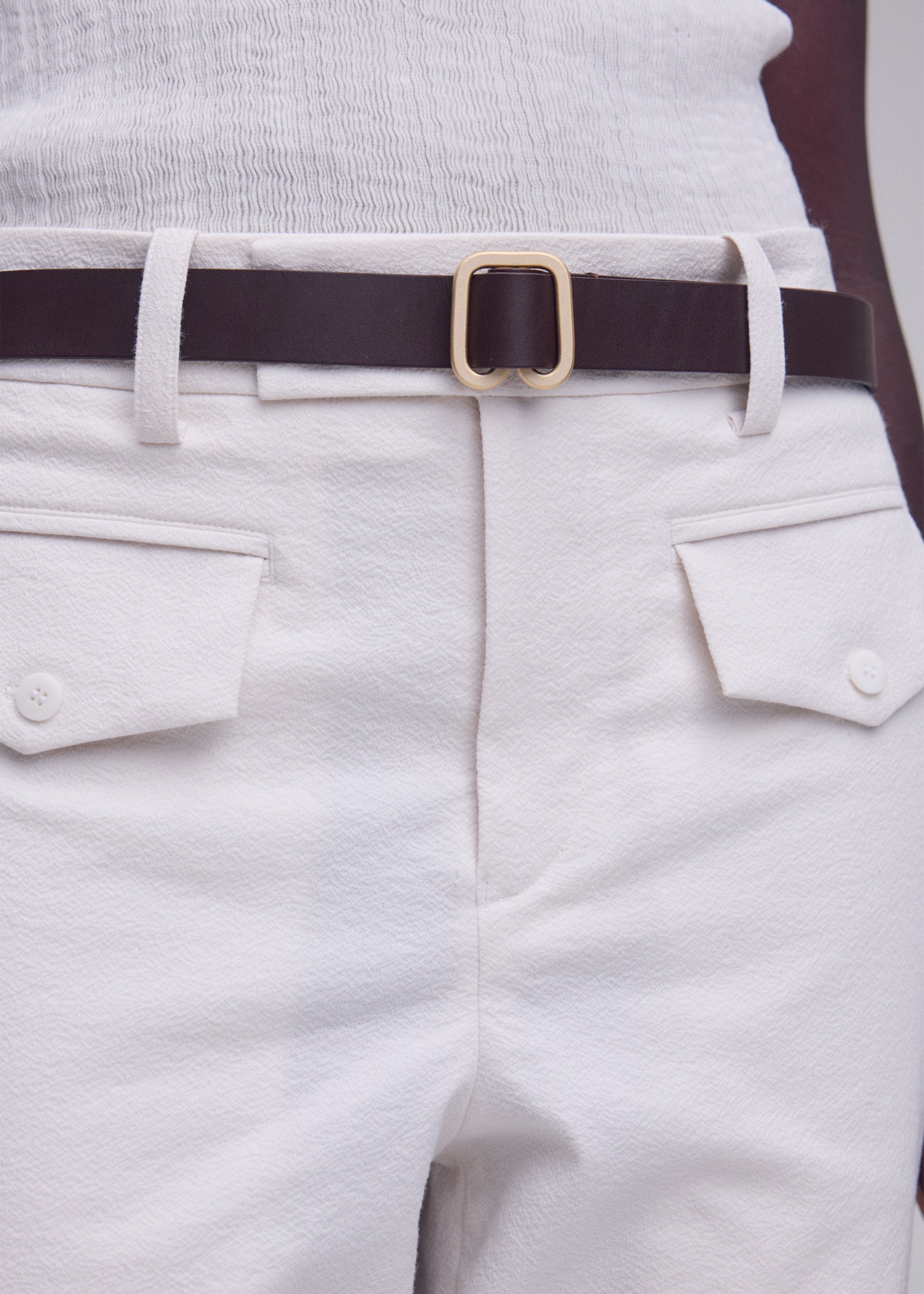 A model wears the ISSEY MIYAKE SOLID LEATHER BELT solid-leather-belt-belt-dull-cream-2.