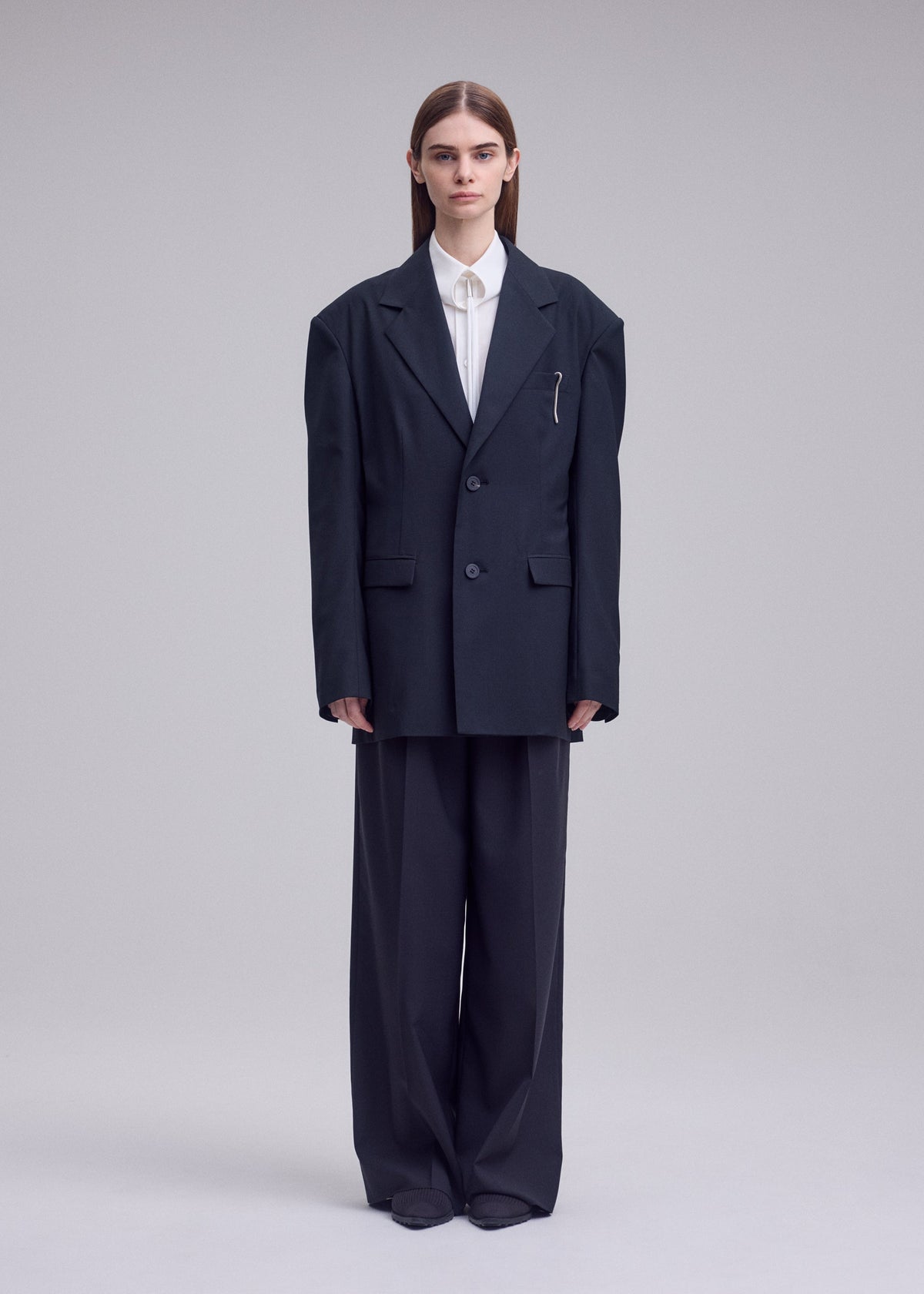 A model wears the ISSEY MIYAKE HONEST ENSEMBLE honest-ensemble-blazer-jacket-black.
