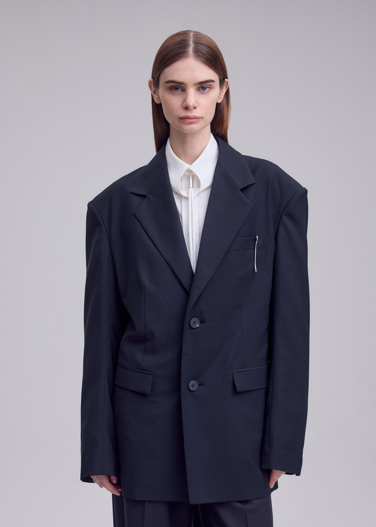 A model wears the ISSEY MIYAKE HONEST ENSEMBLE honest-ensemble-blazer-jacket-black.