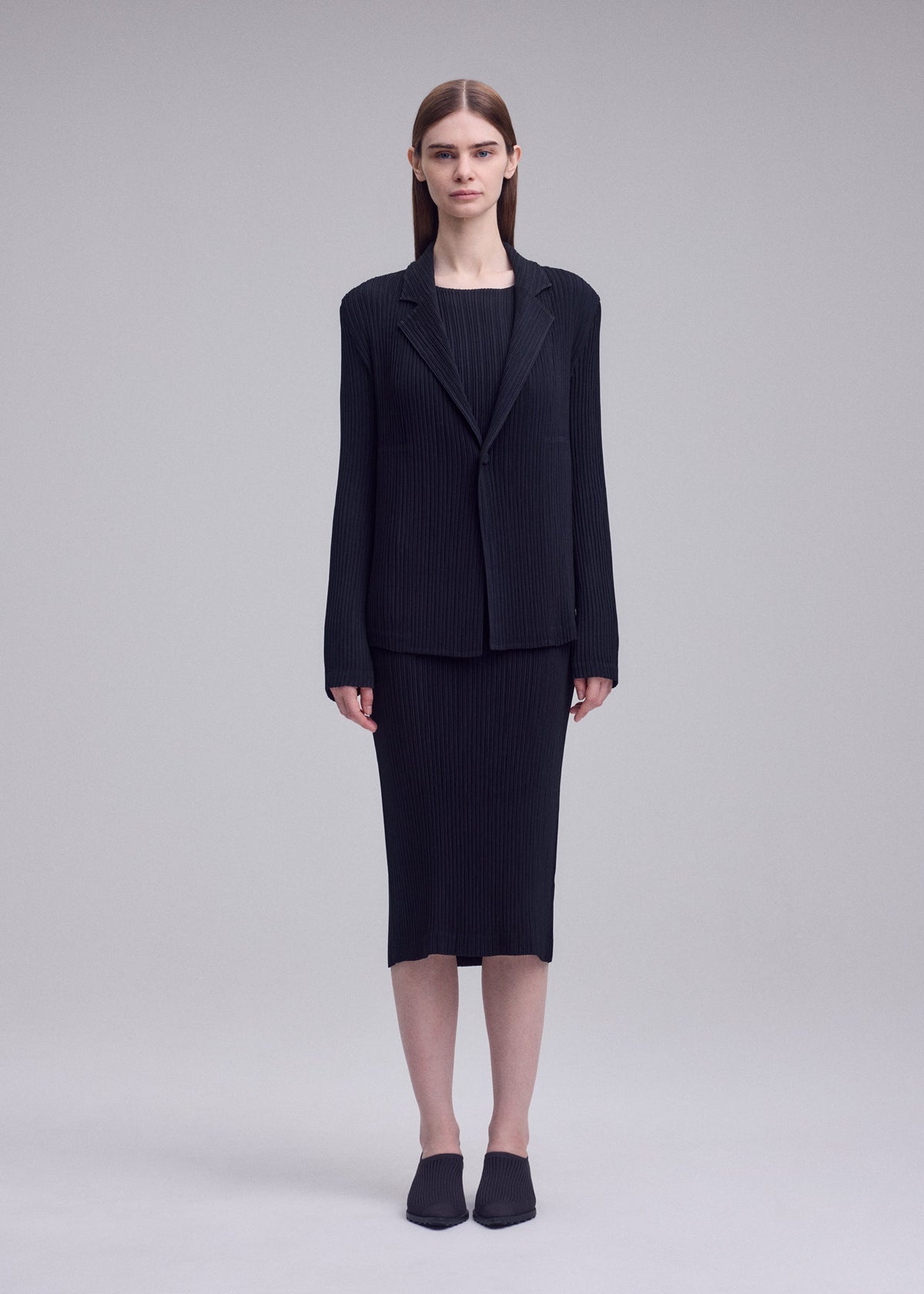 A model wears the ISSEY MIYAKE HATCHING PLEATS hatching-pleats-blazer-style-jacket-grey.