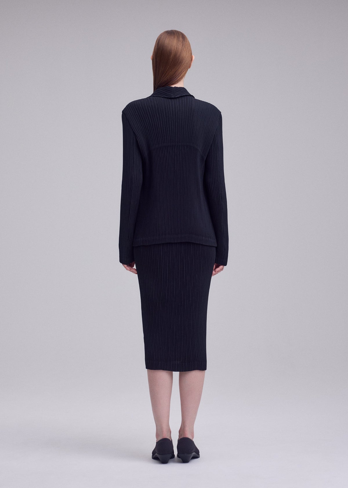 A model wears the ISSEY MIYAKE HATCHING PLEATS hatching-pleats-blazer-style-jacket-grey.