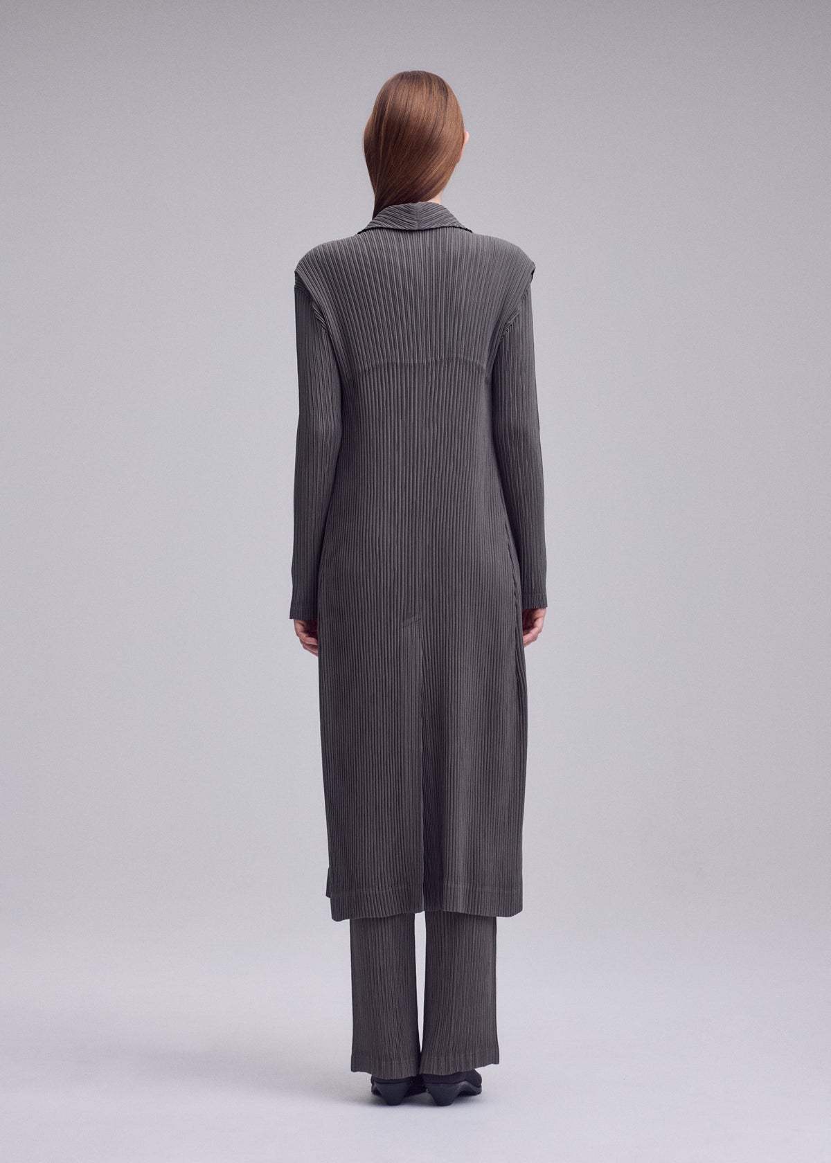 A model wears the ISSEY MIYAKE HATCHING PLEATS hatching-pleats-mid-length-vest-black.