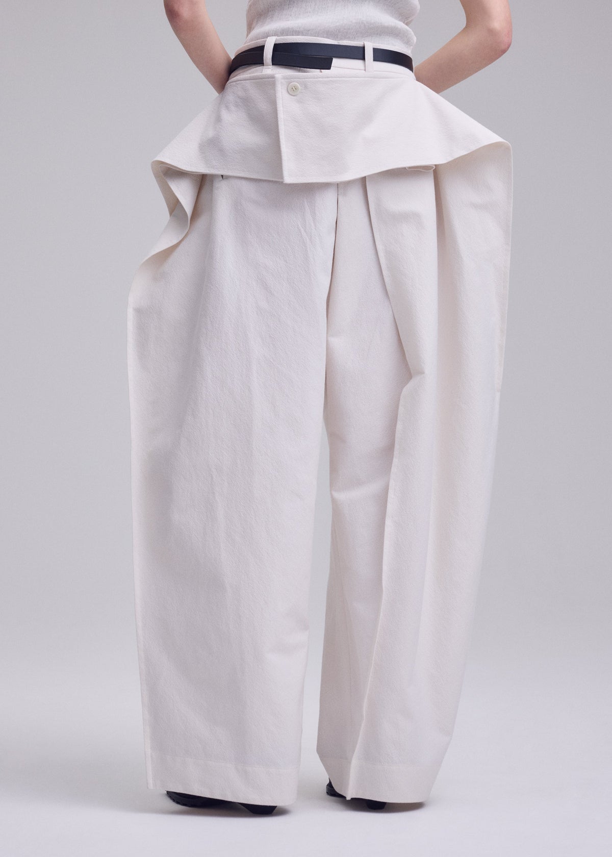 A model wears the ISSEY MIYAKE GRAINY PANTS trousers.