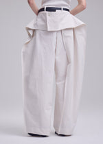 A model wears the ISSEY MIYAKE GRAINY PANTS trousers.