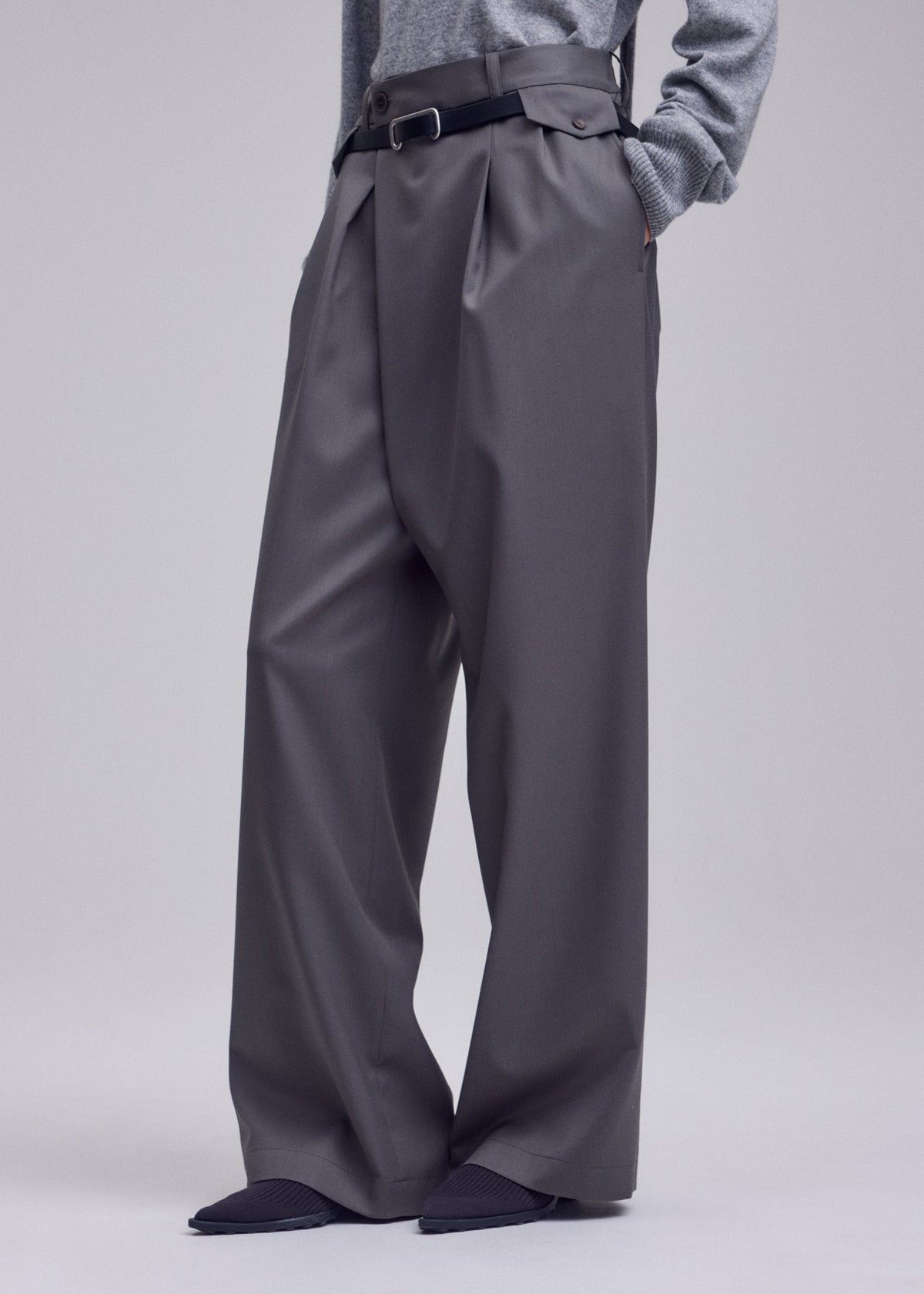 A model wears the ISSEY MIYAKE LUSTROUS WOOL PANTS lustrous-wool-pants-trousers-grey.