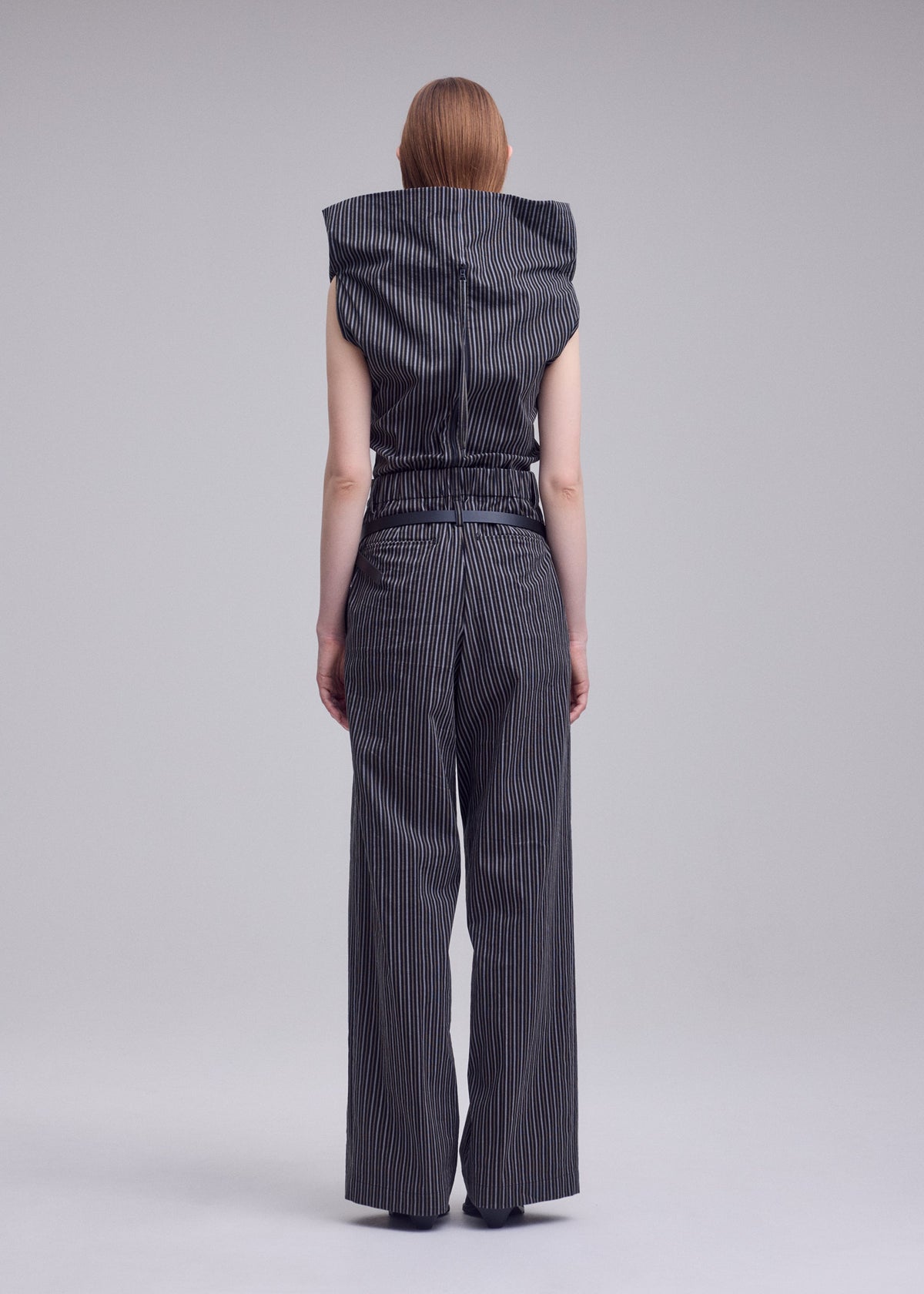 A model wears the ISSEY MIYAKE ALLOW(STRIPE) allow-stripe-trousers-black-hued.