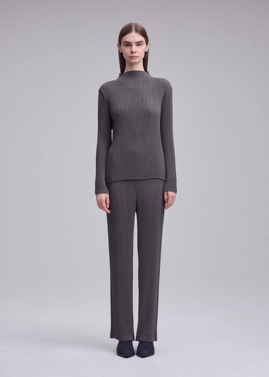 A model wears the ISSEY MIYAKE HATCHING PLEATS hatching-pleats-classic-cut-trousers-grey.
