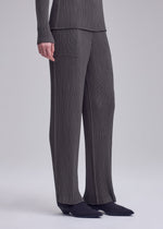 A model wears the ISSEY MIYAKE HATCHING PLEATS hatching-pleats-classic-cut-trousers-grey.
