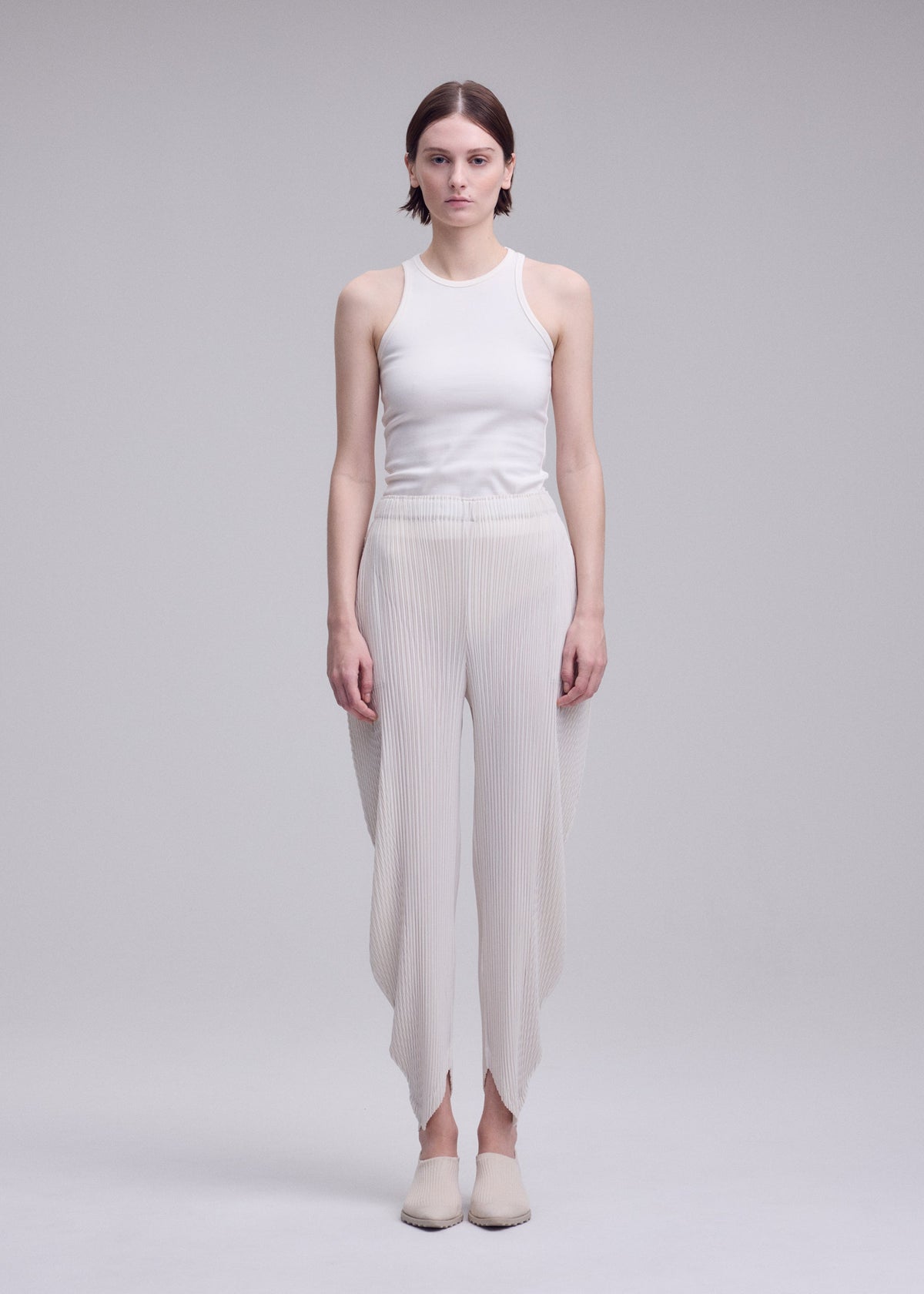 A model wears the ISSEY MIYAKE LEAF PLEATS leaf-pleats-trousers-dark-navy.