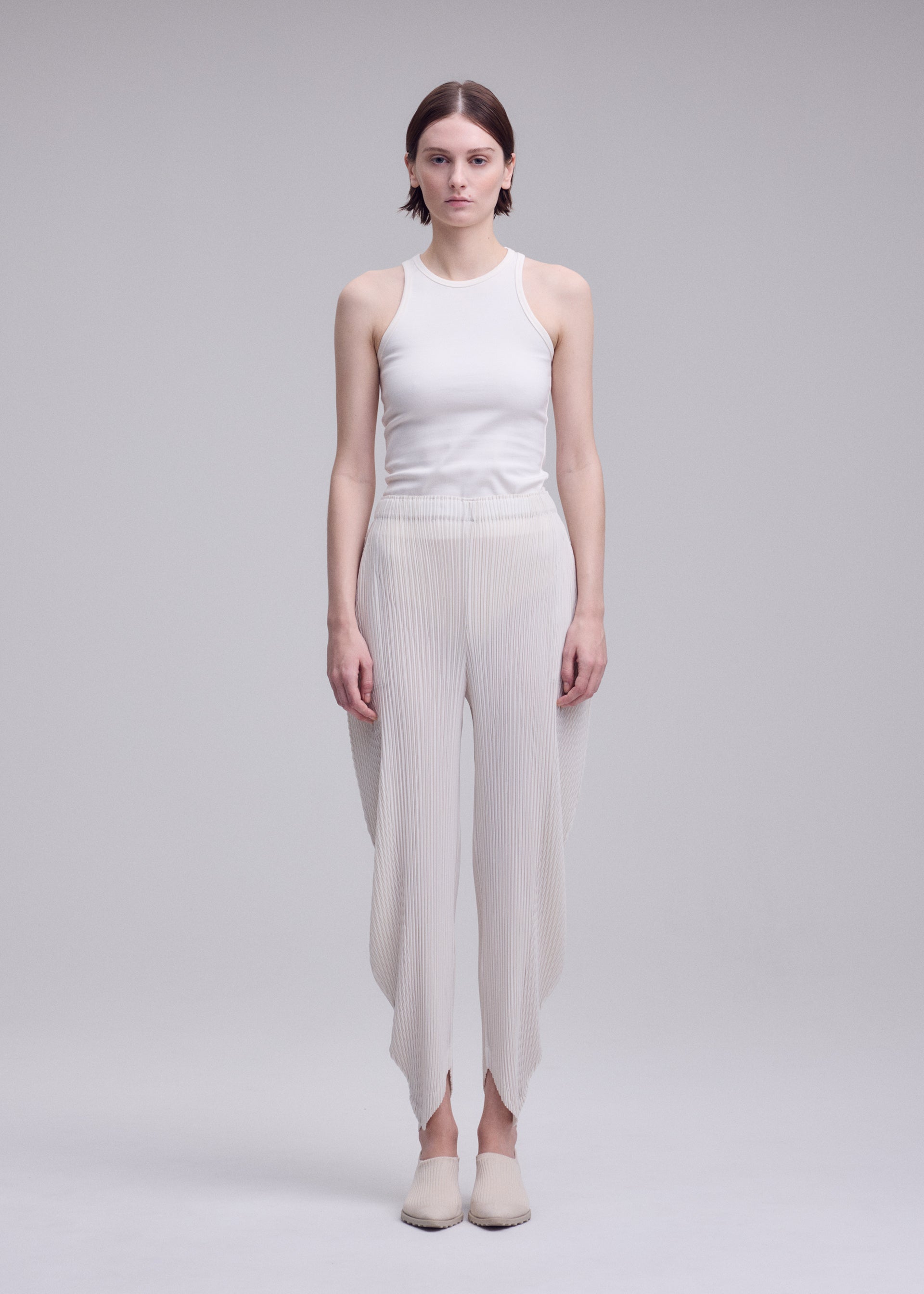 A model wears the ISSEY MIYAKE LEAF PLEATS leaf-pleats-trousers-dark-navy.