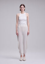 A model wears the ISSEY MIYAKE LEAF PLEATS leaf-pleats-trousers-off-white.
