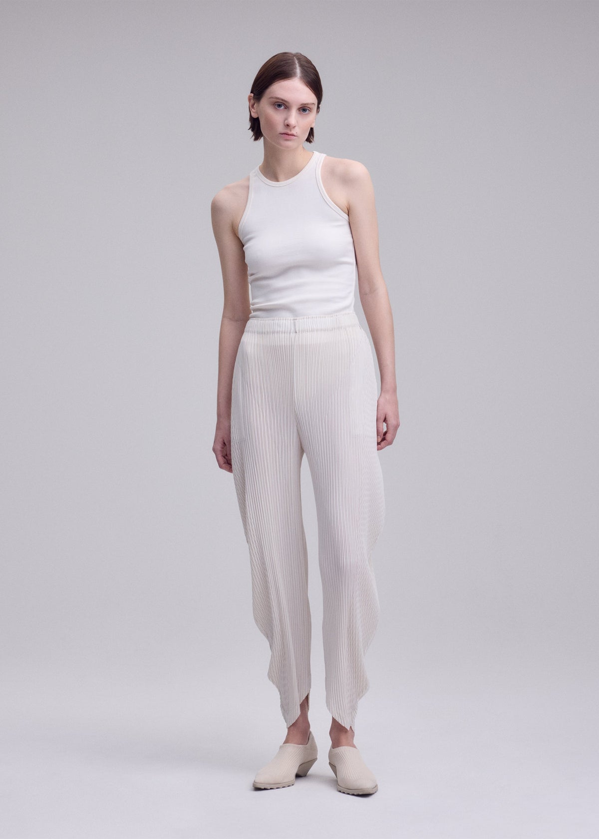 A model wears the ISSEY MIYAKE LEAF PLEATS leaf-pleats-trousers-dark-navy.