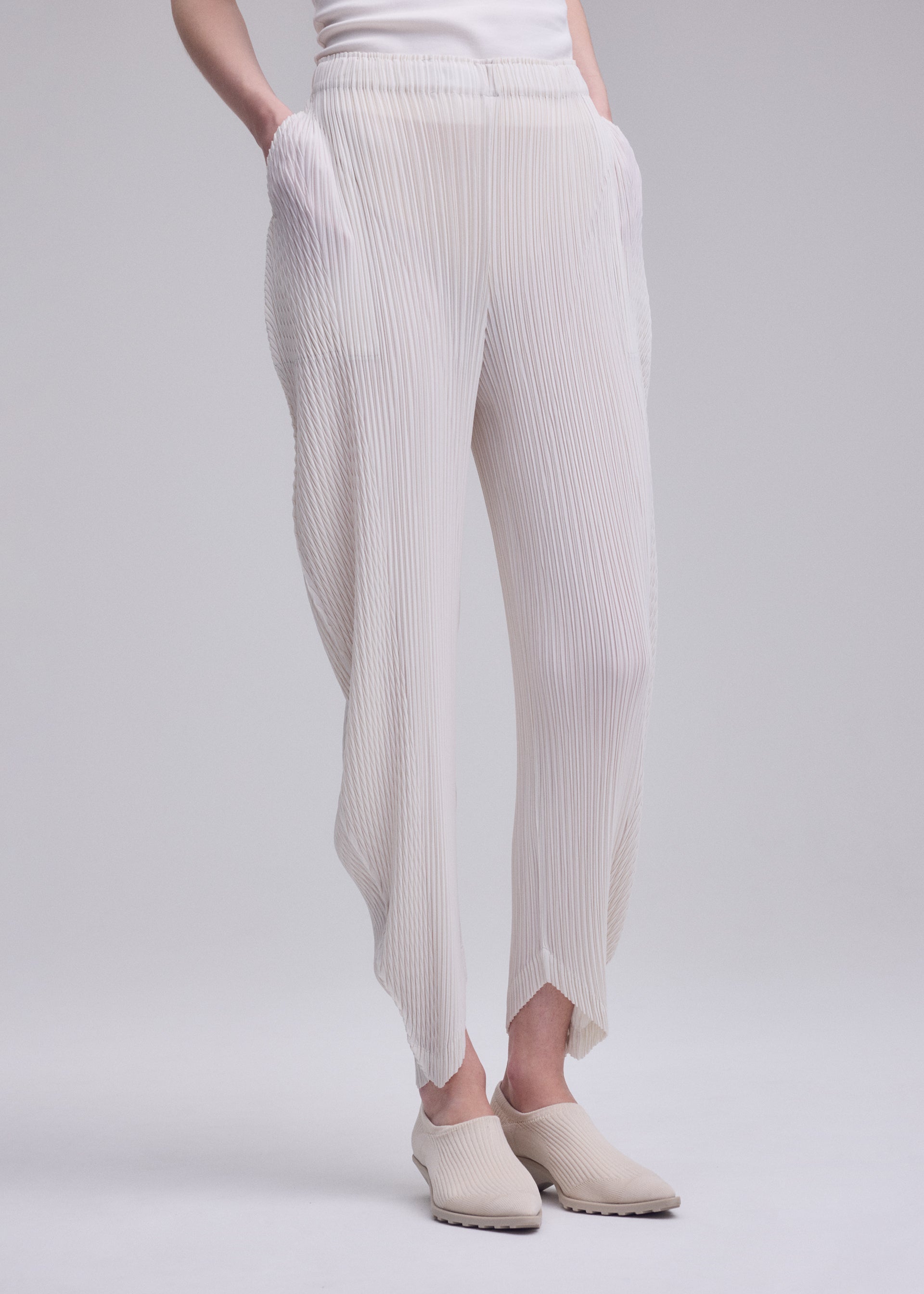 A model wears the ISSEY MIYAKE LEAF PLEATS leaf-pleats-trousers-dark-navy.