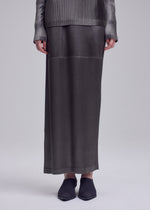 A model wears the ISSEY MIYAKE GLOSSED PANELS PLEATS glossed-panels-pleats-skirt-light-pink.
