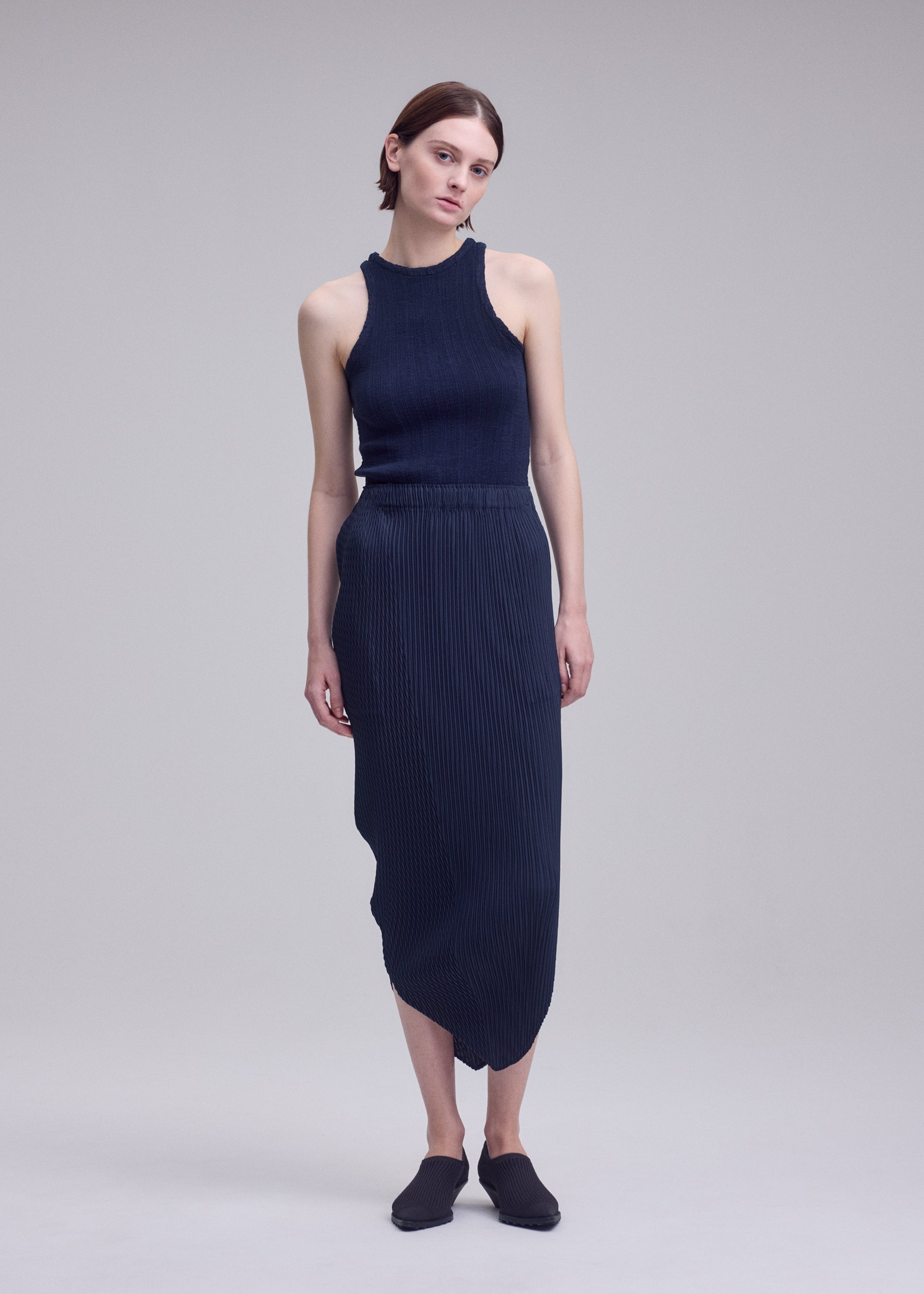 A model wears the ISSEY MIYAKE LEAF PLEATS leaf-pleats-skirt-dark-navy.