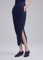 A model wears the ISSEY MIYAKE LEAF PLEATS leaf-pleats-skirt-dark-navy.